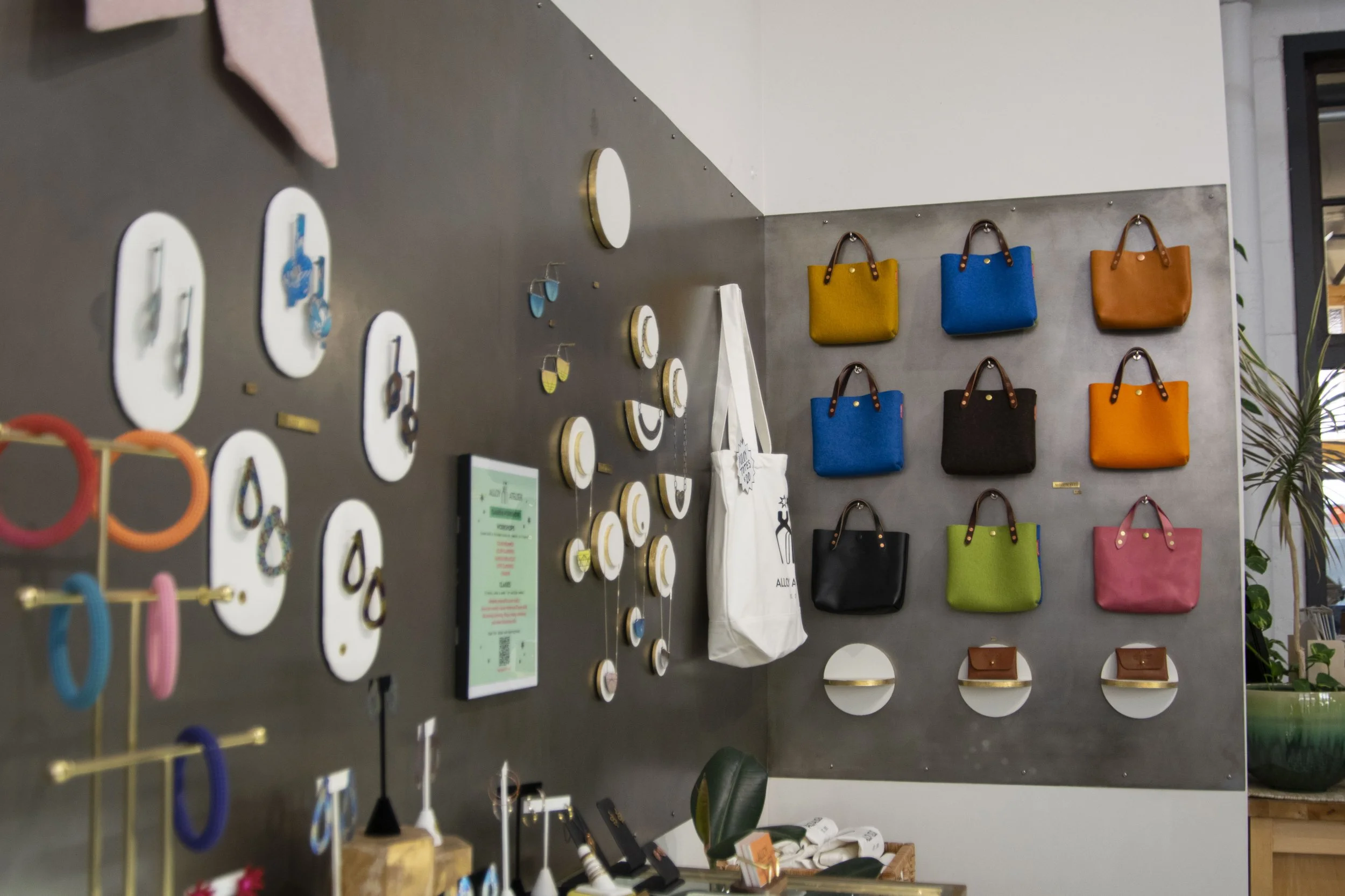 Gray steel wall with purses and jewelry hung on it. 