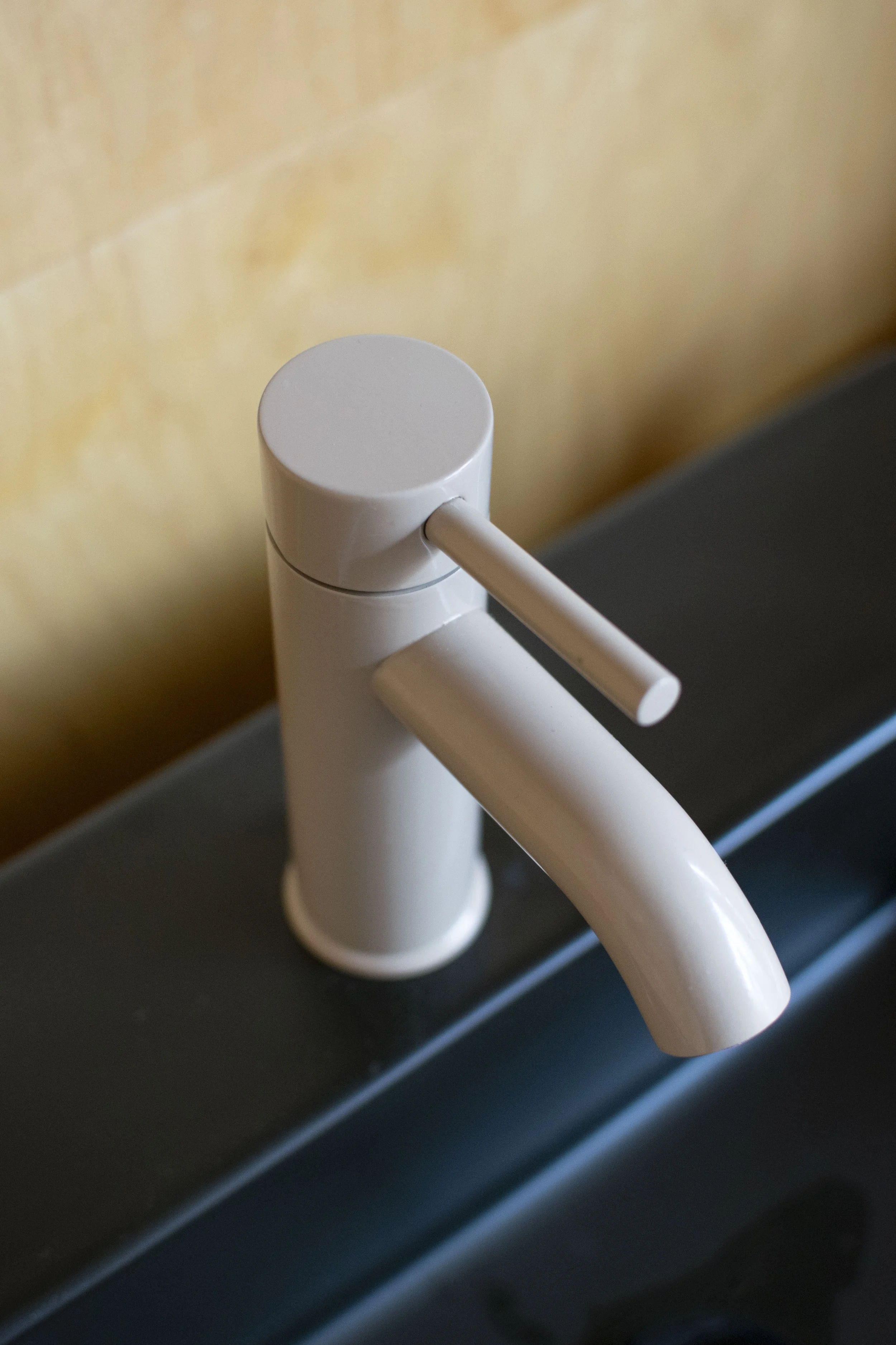 Modern style faucet with a beige powder coat finish. Mounted into a black sink.