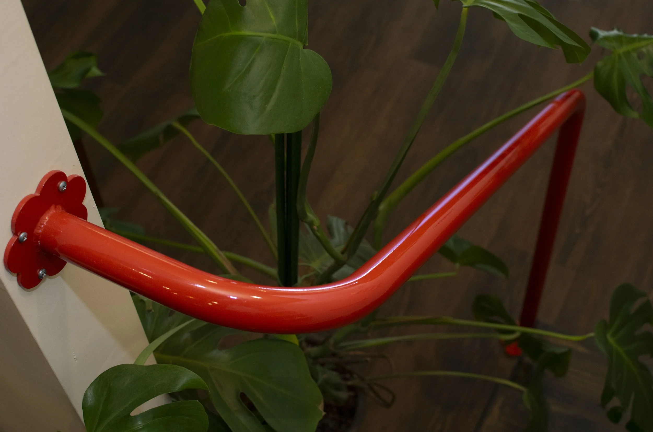 Bold red hand rails with flower brackets mounting to wall and floor.