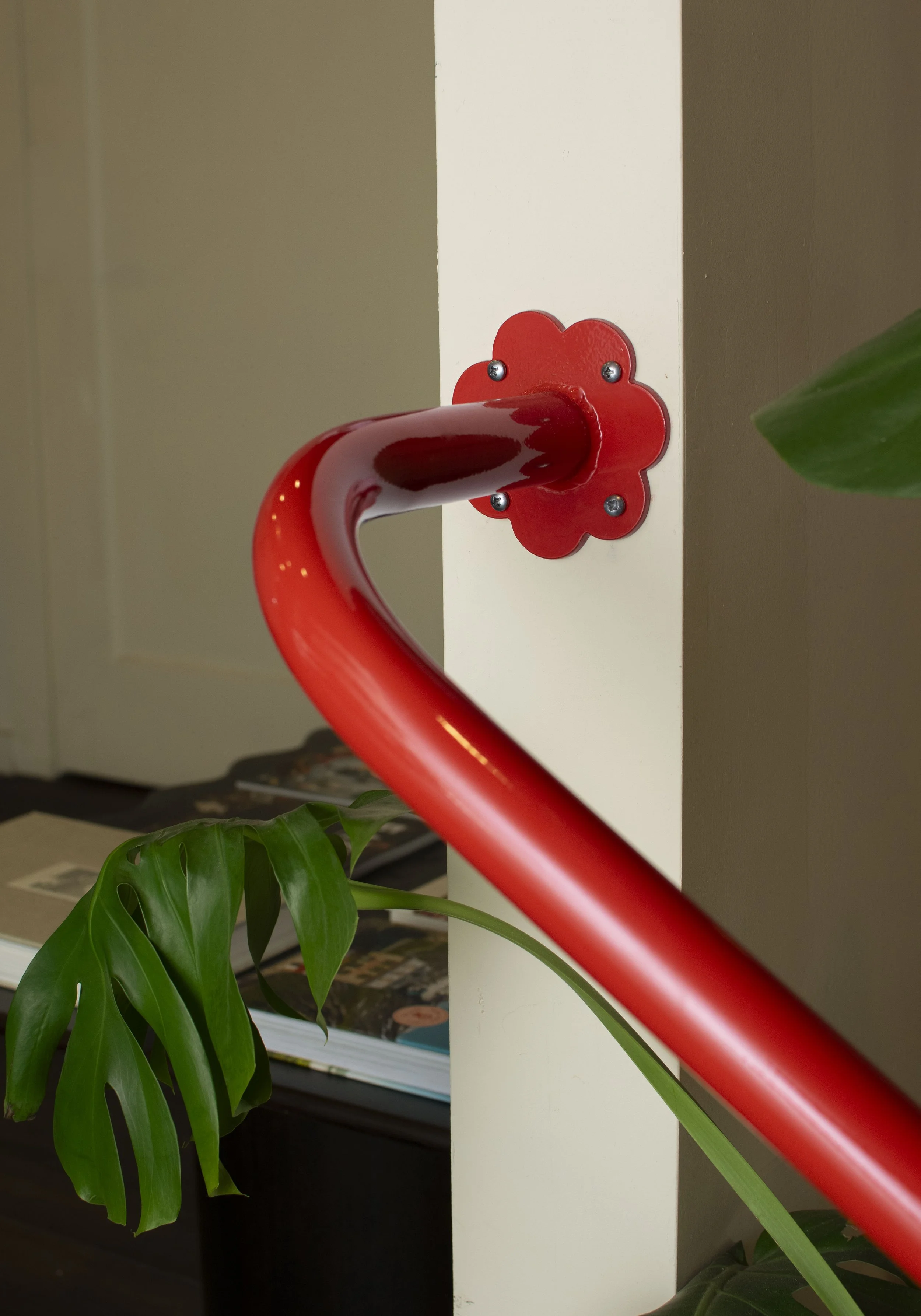 Bold red hand rails with flower brackets mounting to wall and floor.