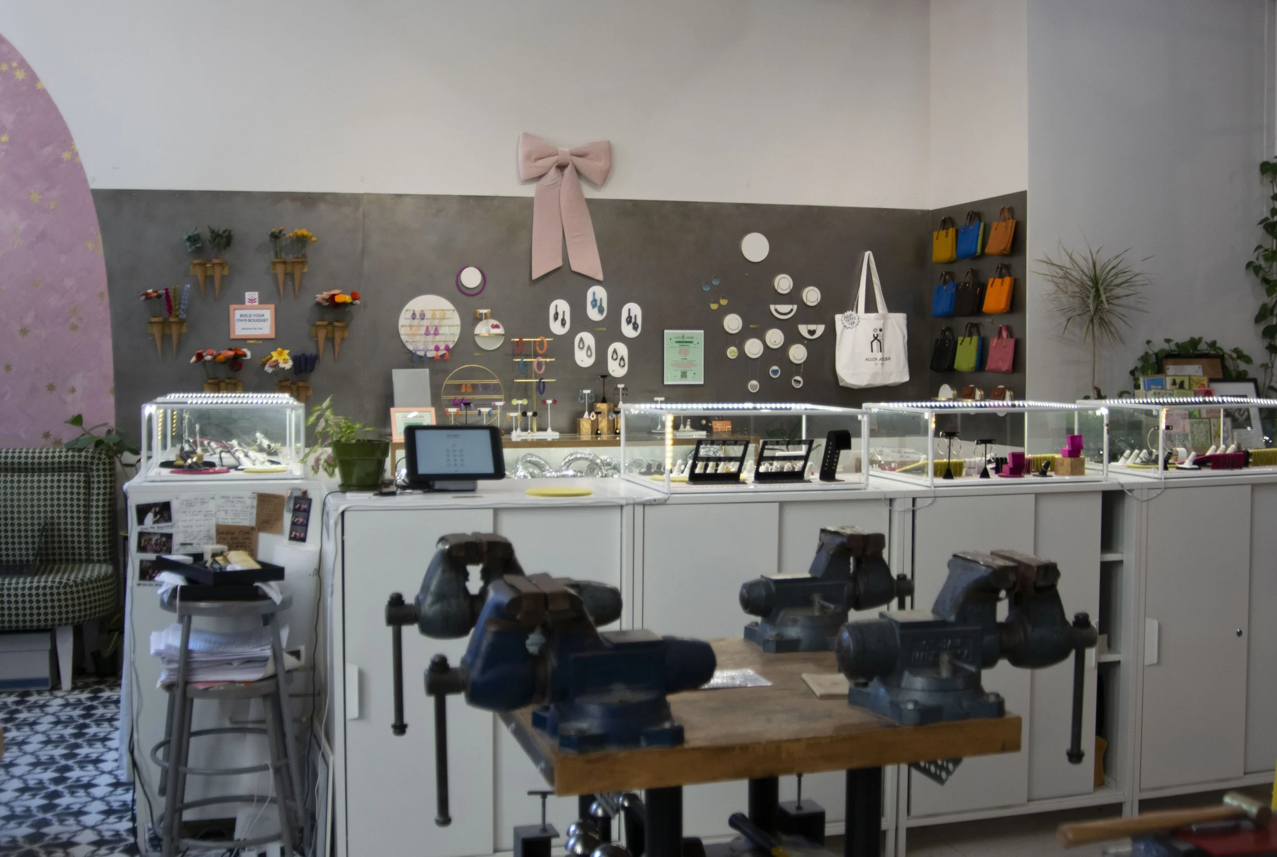 Gray steel wall with purses and jewelry hung on it. 