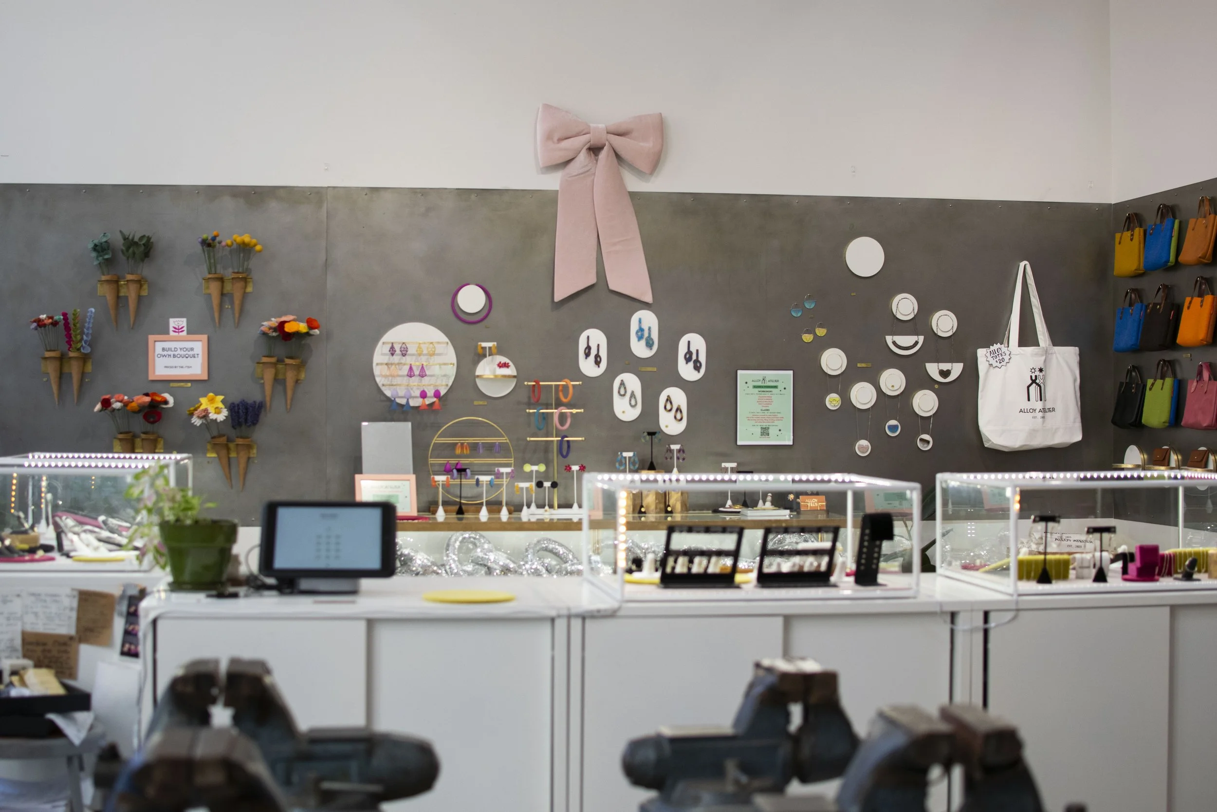 Gray steel wall with purses and jewelry hung on it. 