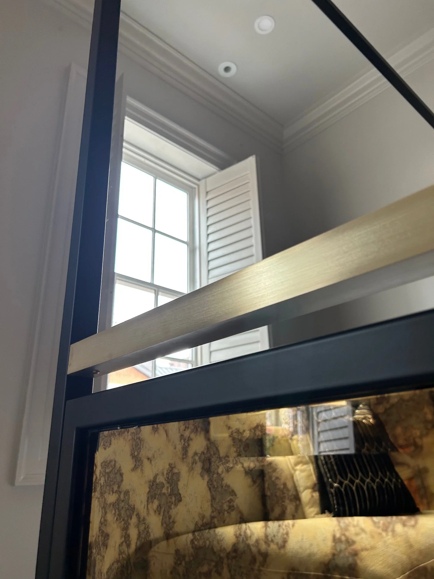 Detail of steel, brass and antique mirror on king sized bed.