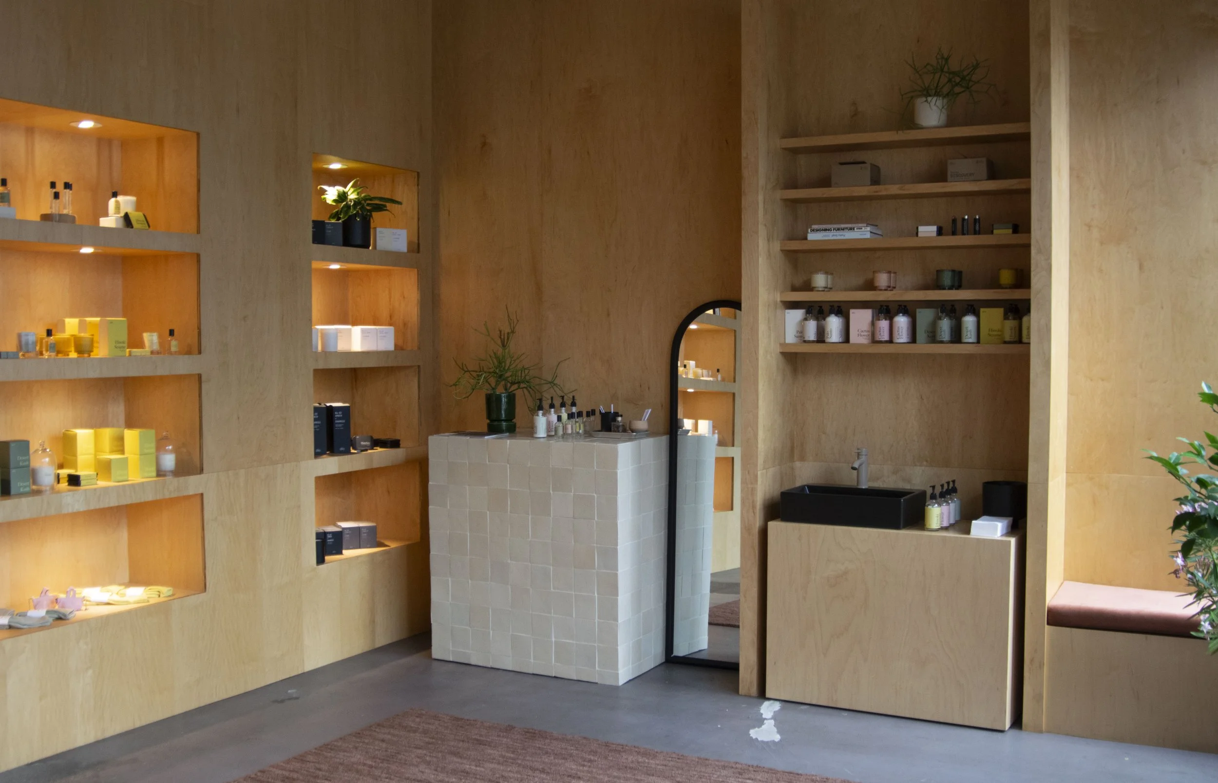 Plywood walls with built in, lit shelving holding Dilo products.