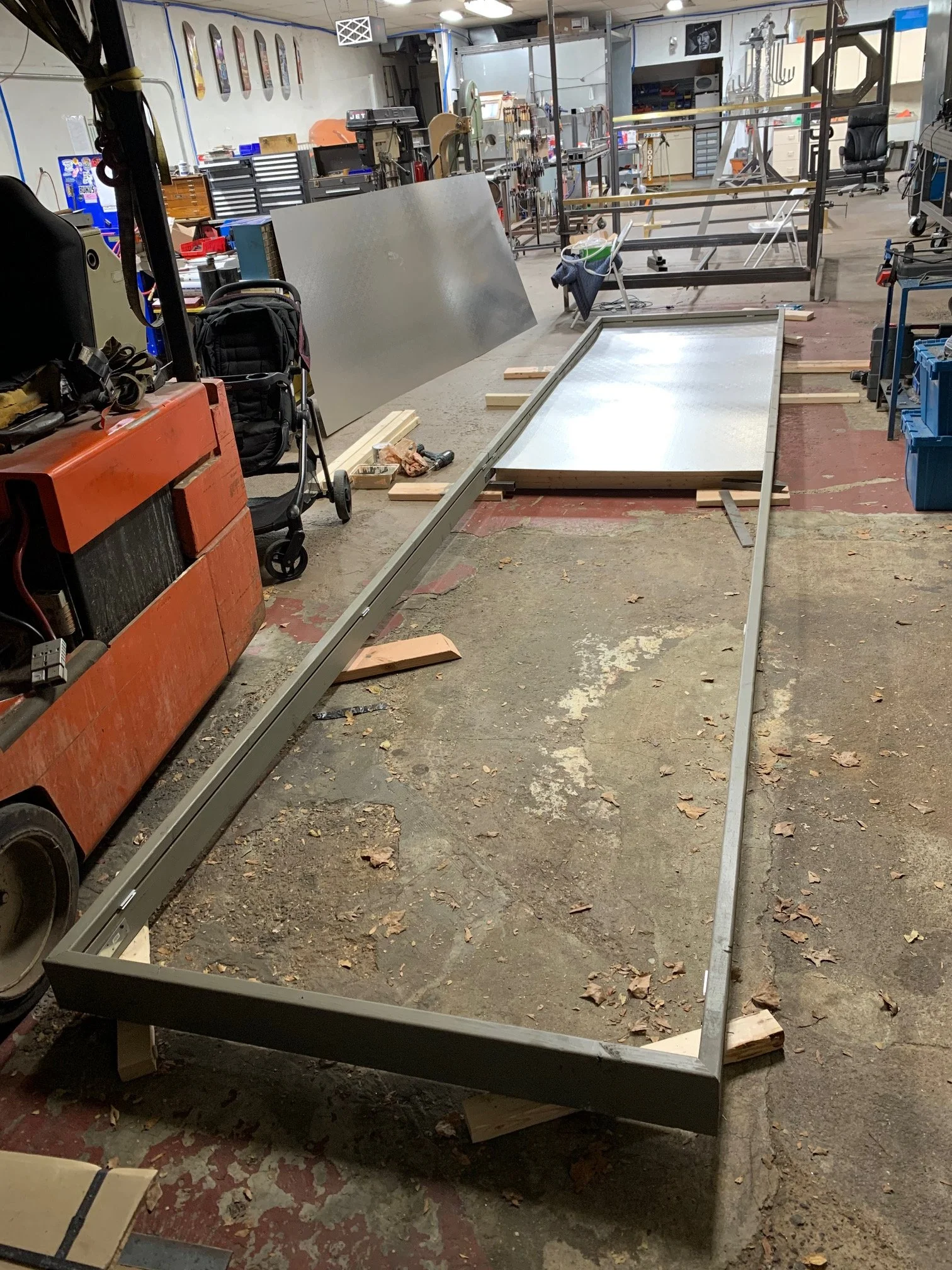 A cluttered workshop or garage with metal frames, tools, and equipment in an organized workspace.