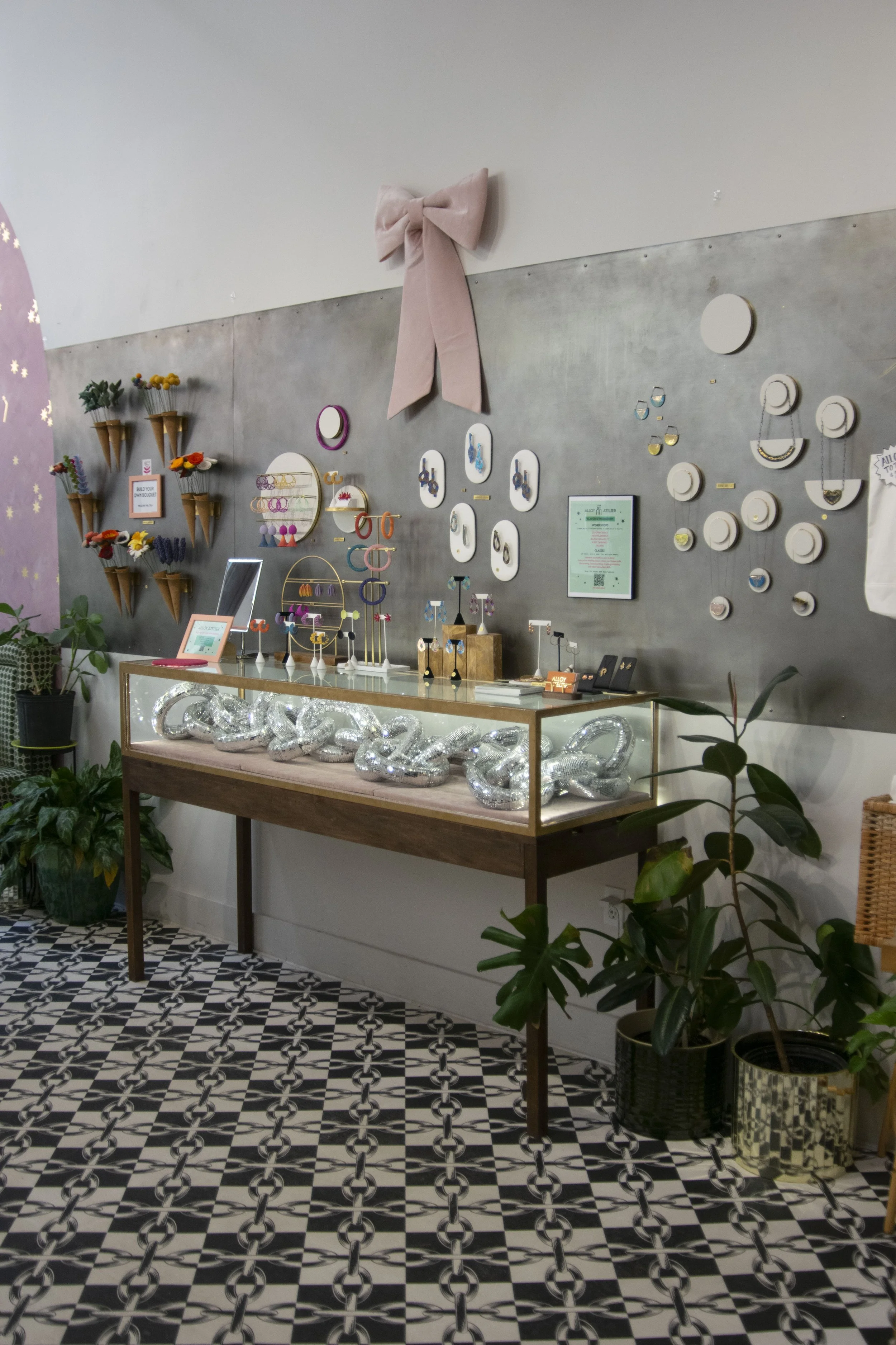 Gray steel wall with purses and jewelry hung on it. 