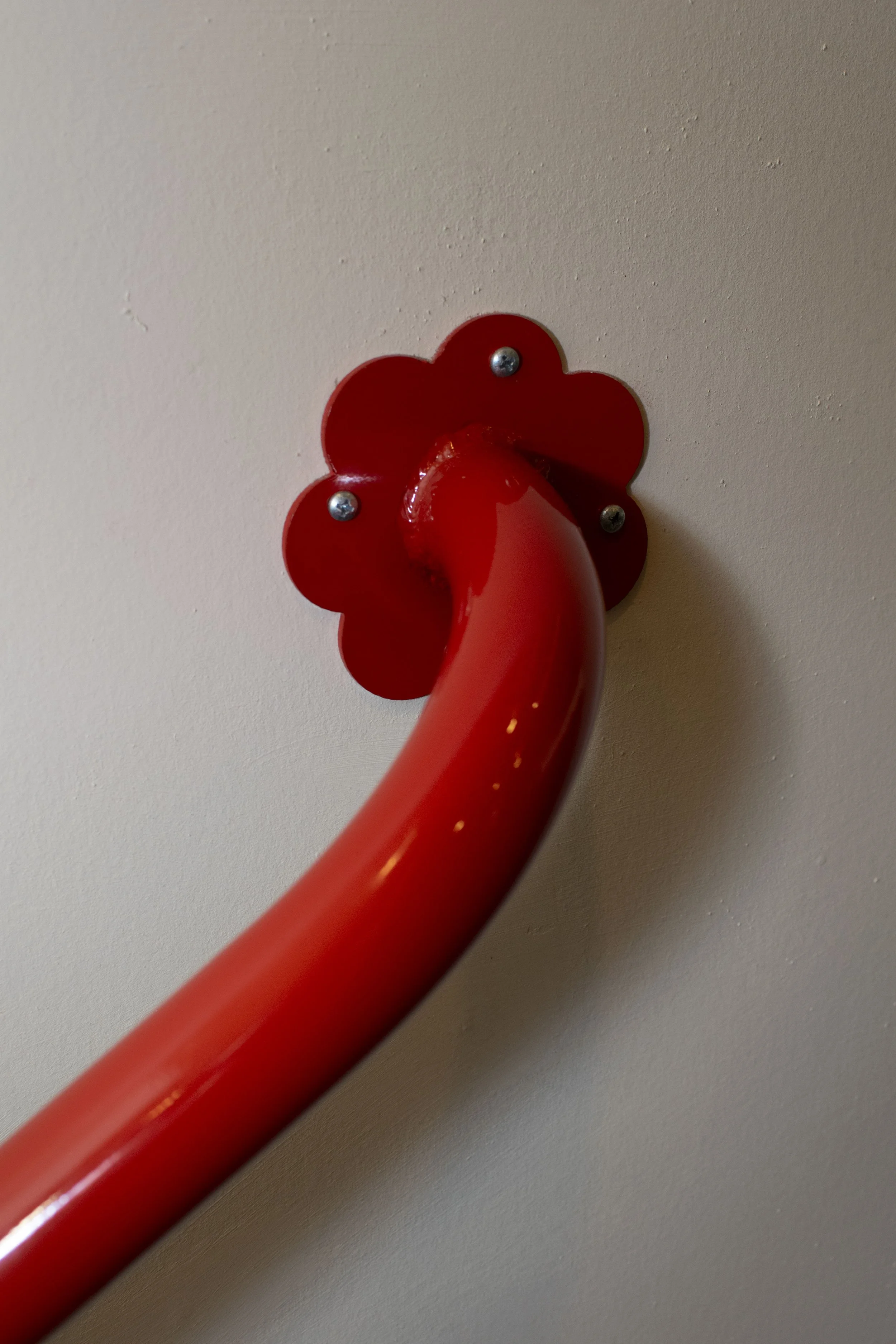 Bold red hand rails with flower brackets mounting to wall and floor.