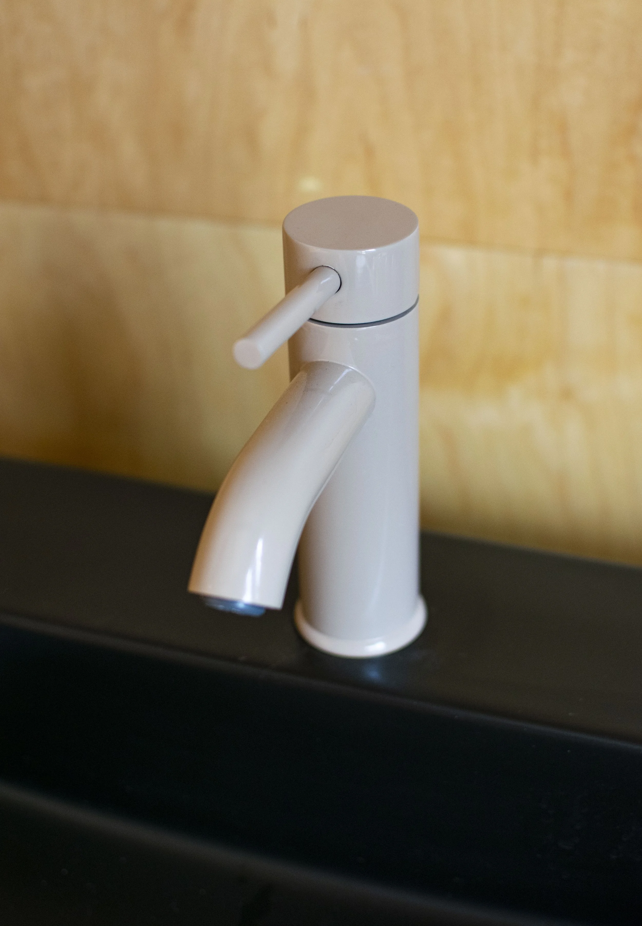 Modern style faucet with a beige powder coat finish. Mounted into a black sink.