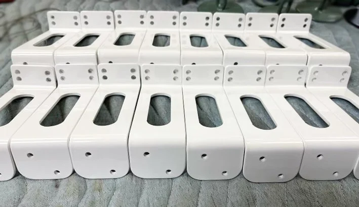 An organized group of bent steel brackets with a white powder coat finish