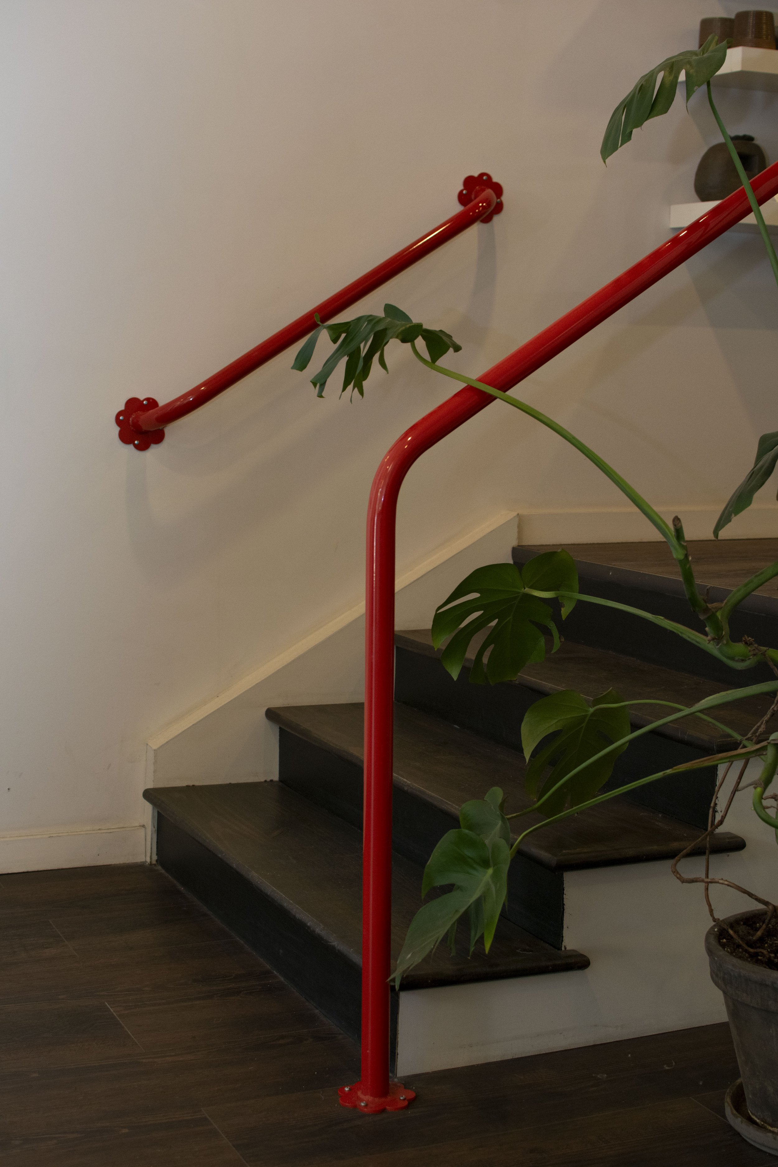 Bold red hand rails with flower brackets mounting to wall and floor.