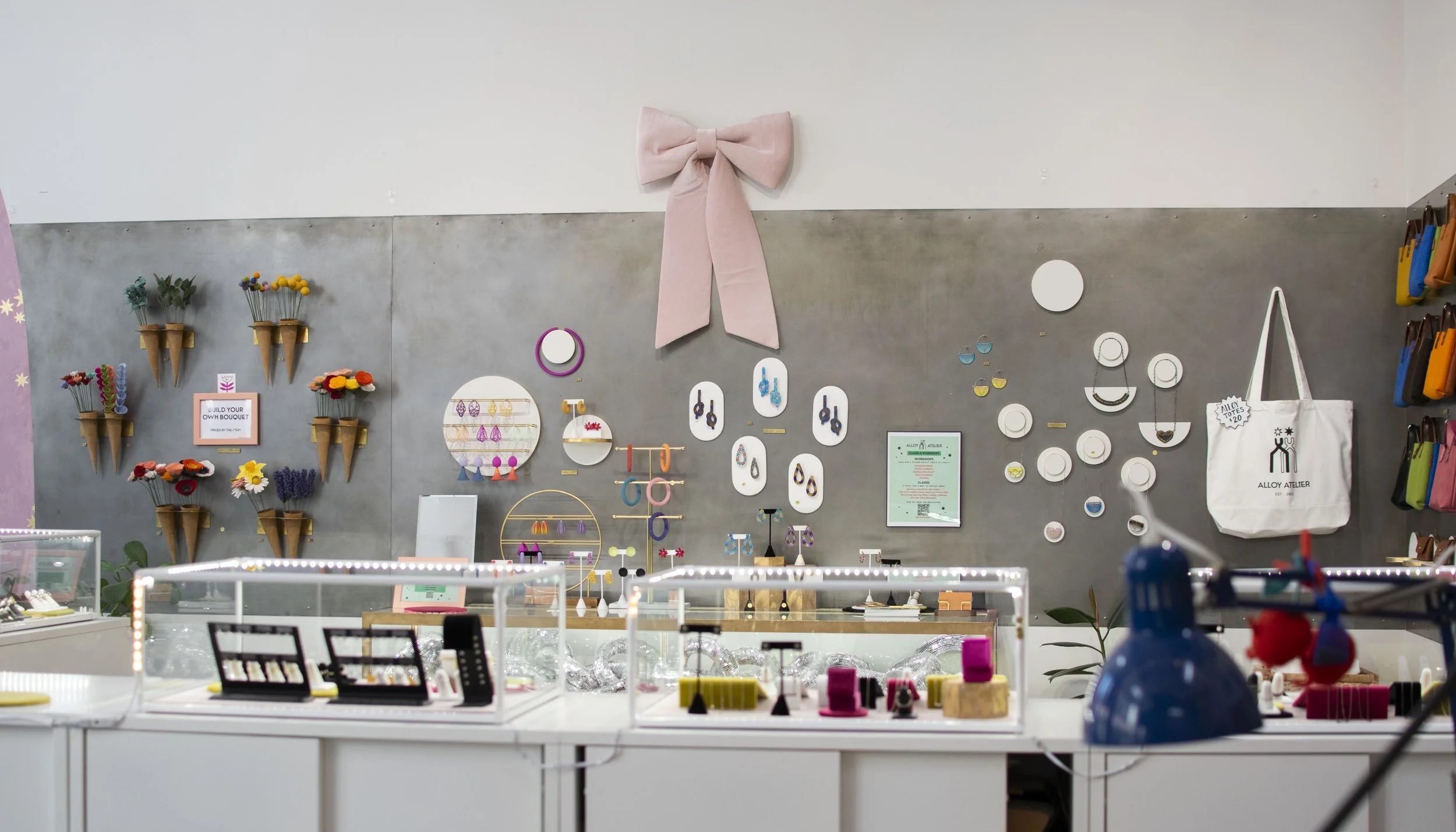 Gray steel wall with purses and jewelry hung on it. 