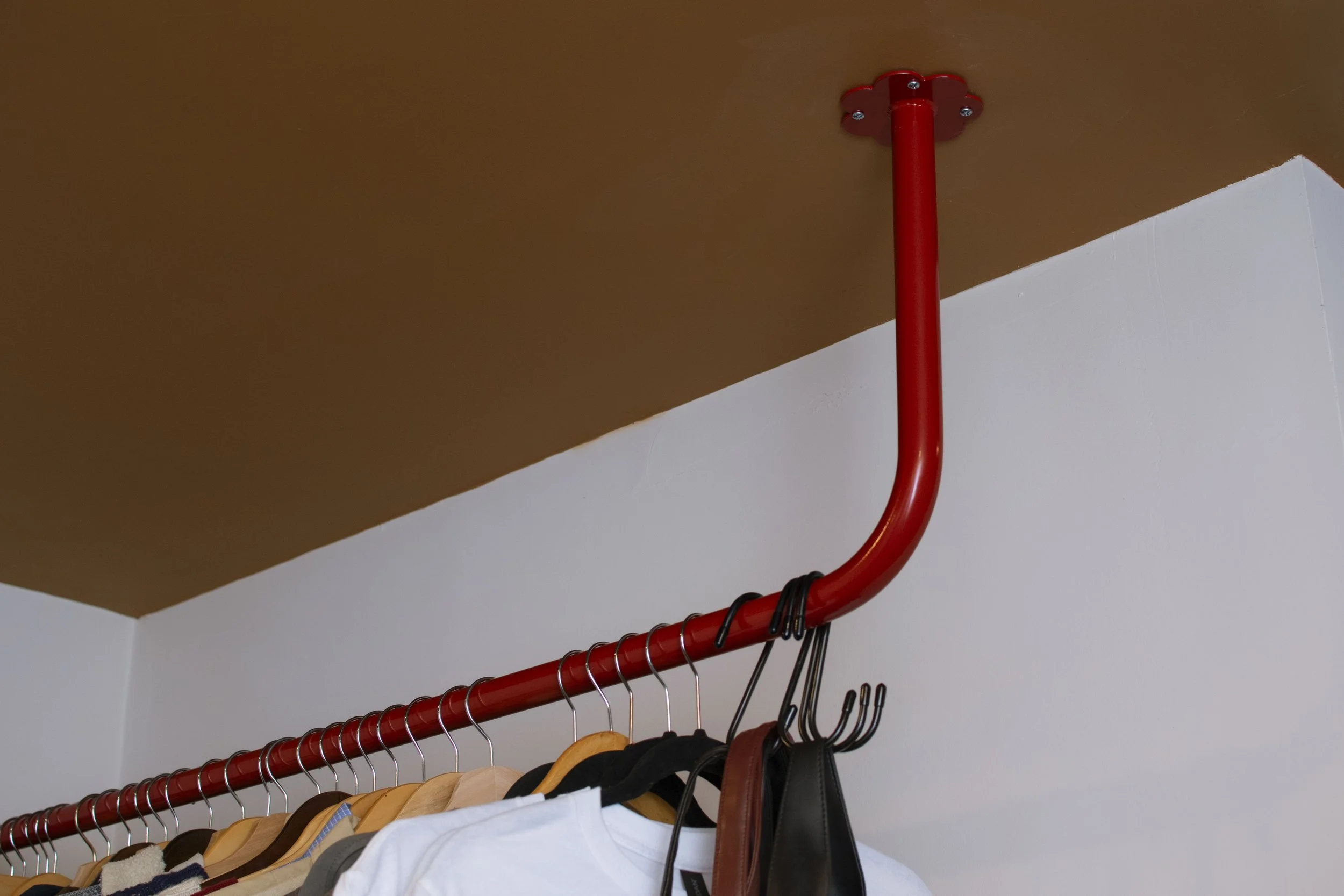 Red clothing bar mounting into tan ceiling