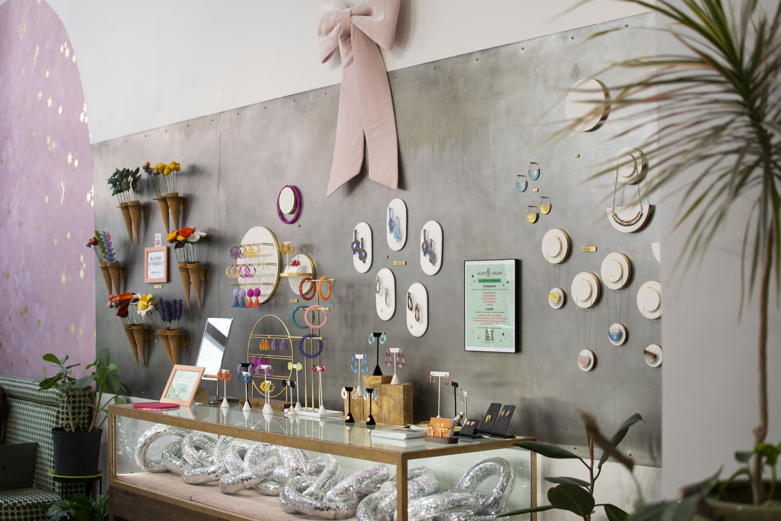 Gray steel wall with purses and jewelry hung on it. 