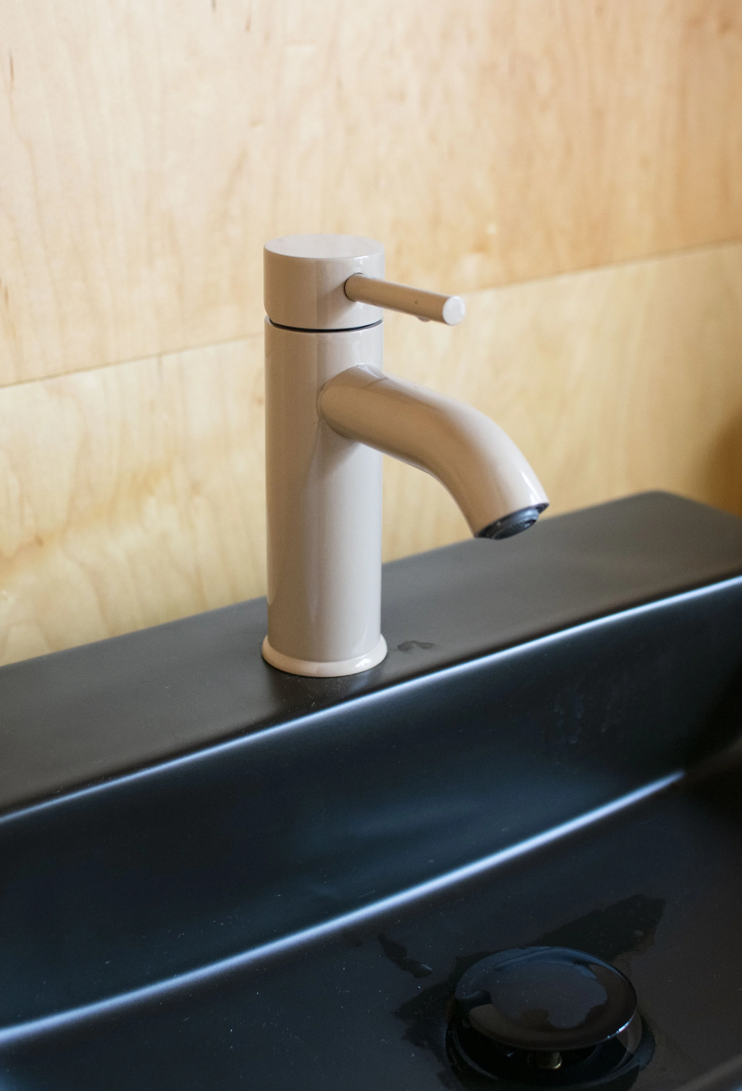 Modern style faucet with a beige powder coat finish. Mounted into a black sink.