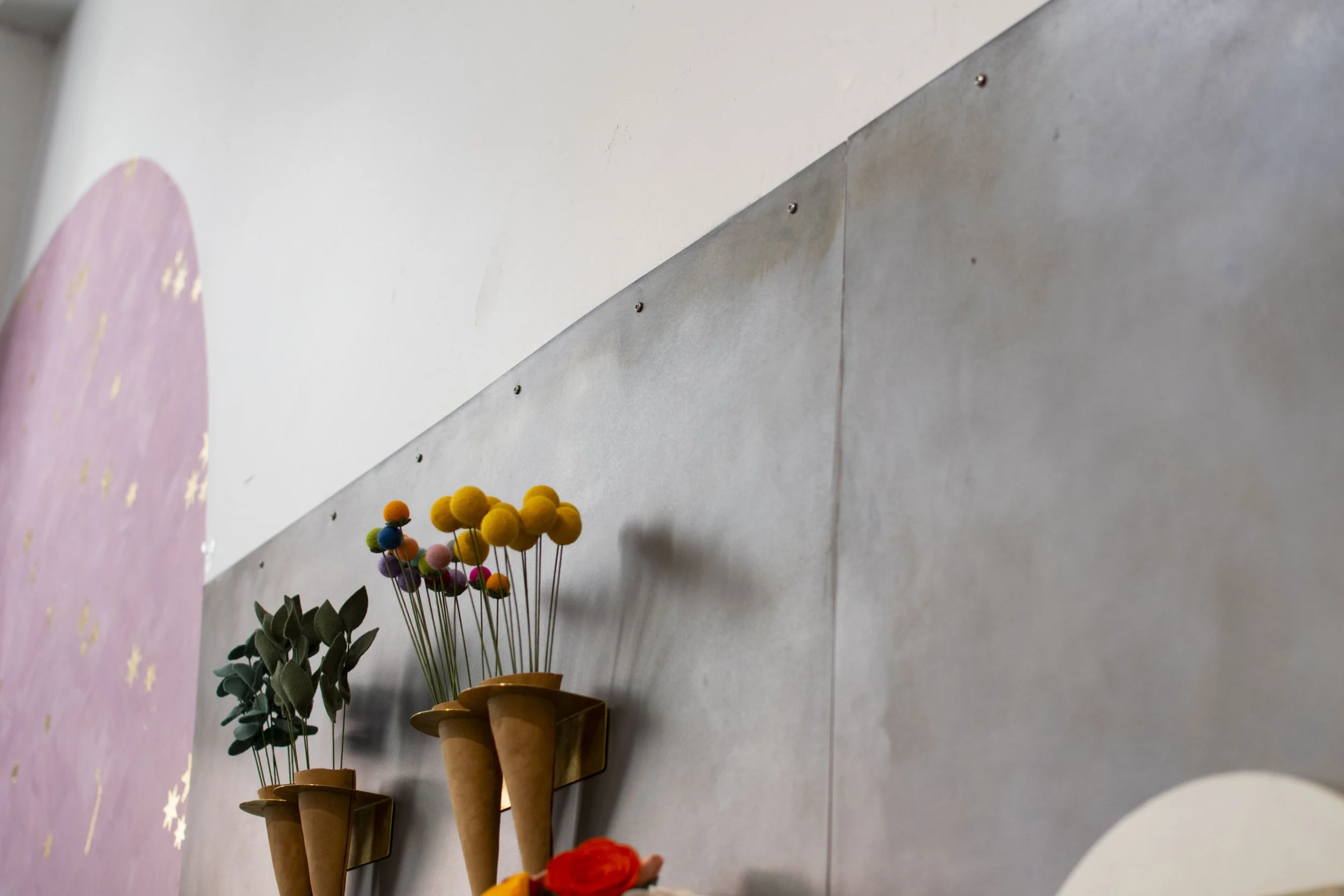 Detail of gray steel wall with purses and jewelry hung on it. 