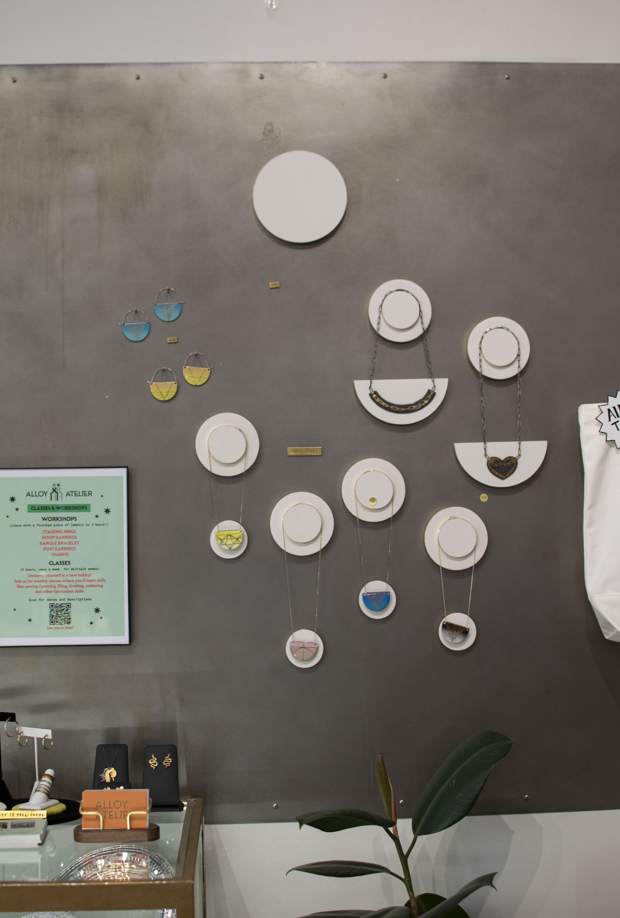 Detail of gray steel wall with purses and jewelry hung on it. 