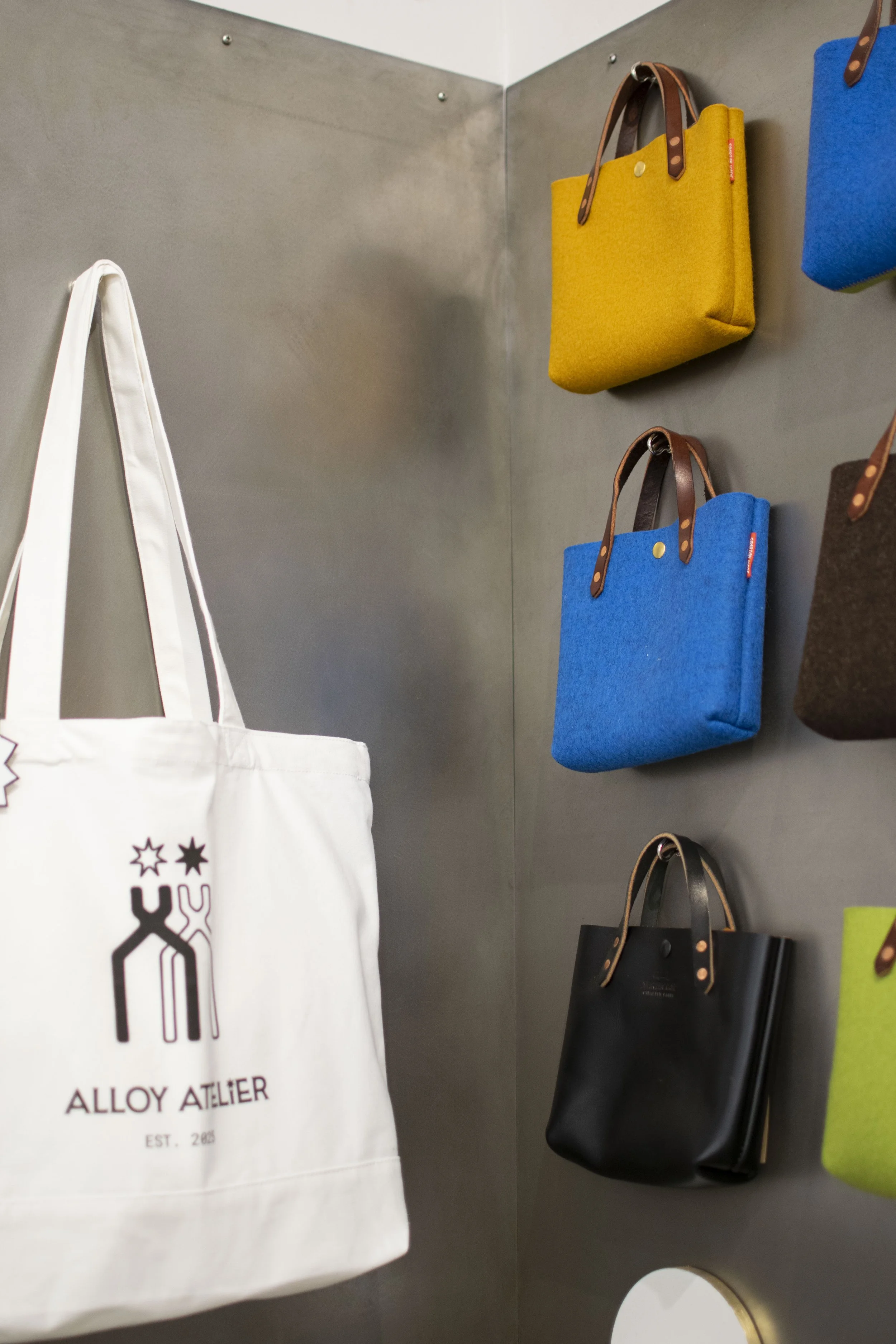 Detail of gray steel wall with purses and jewelry hung on it. 