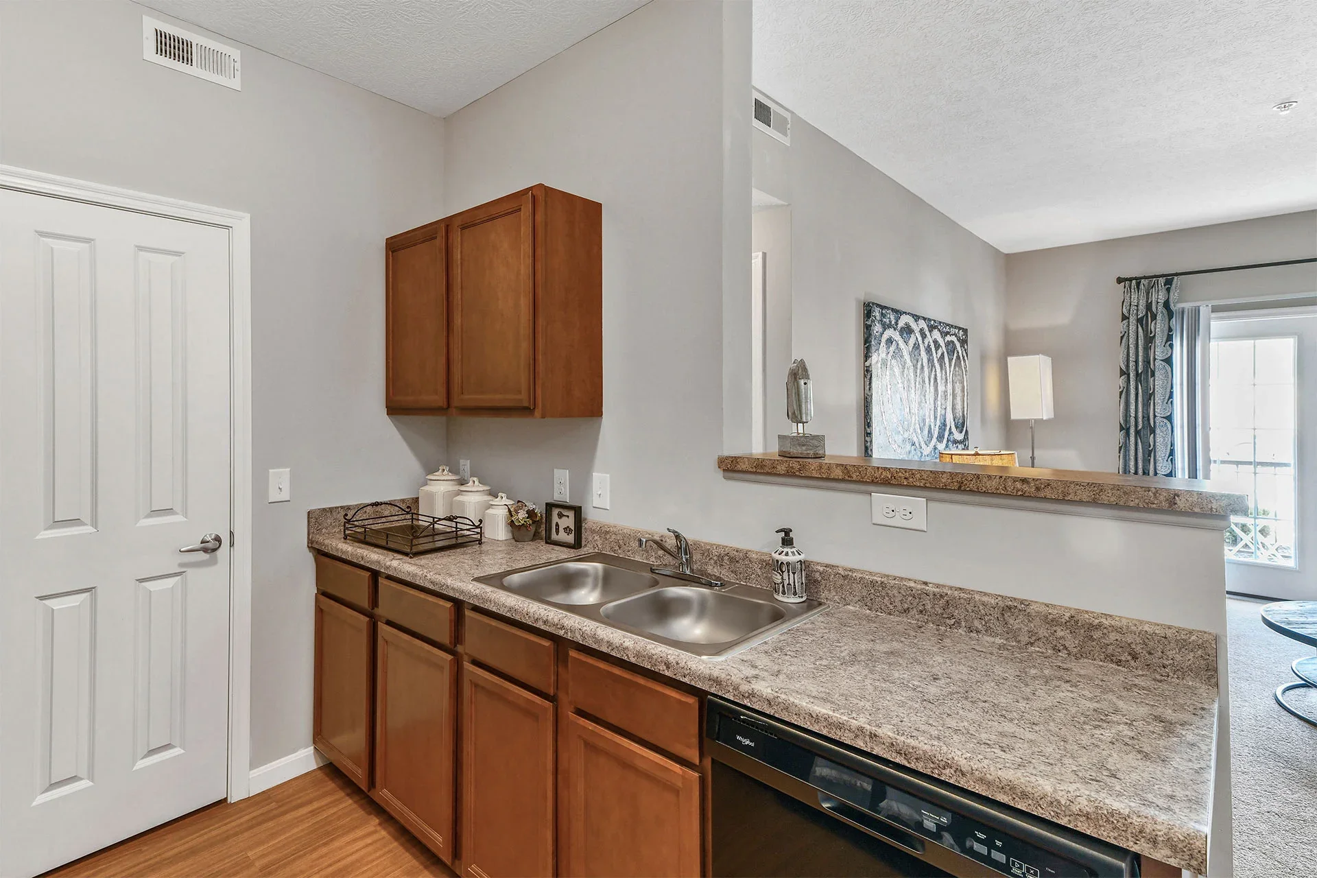 Kitchen with granite countertops, double sink, wooden cabinets, and a pass-through window.