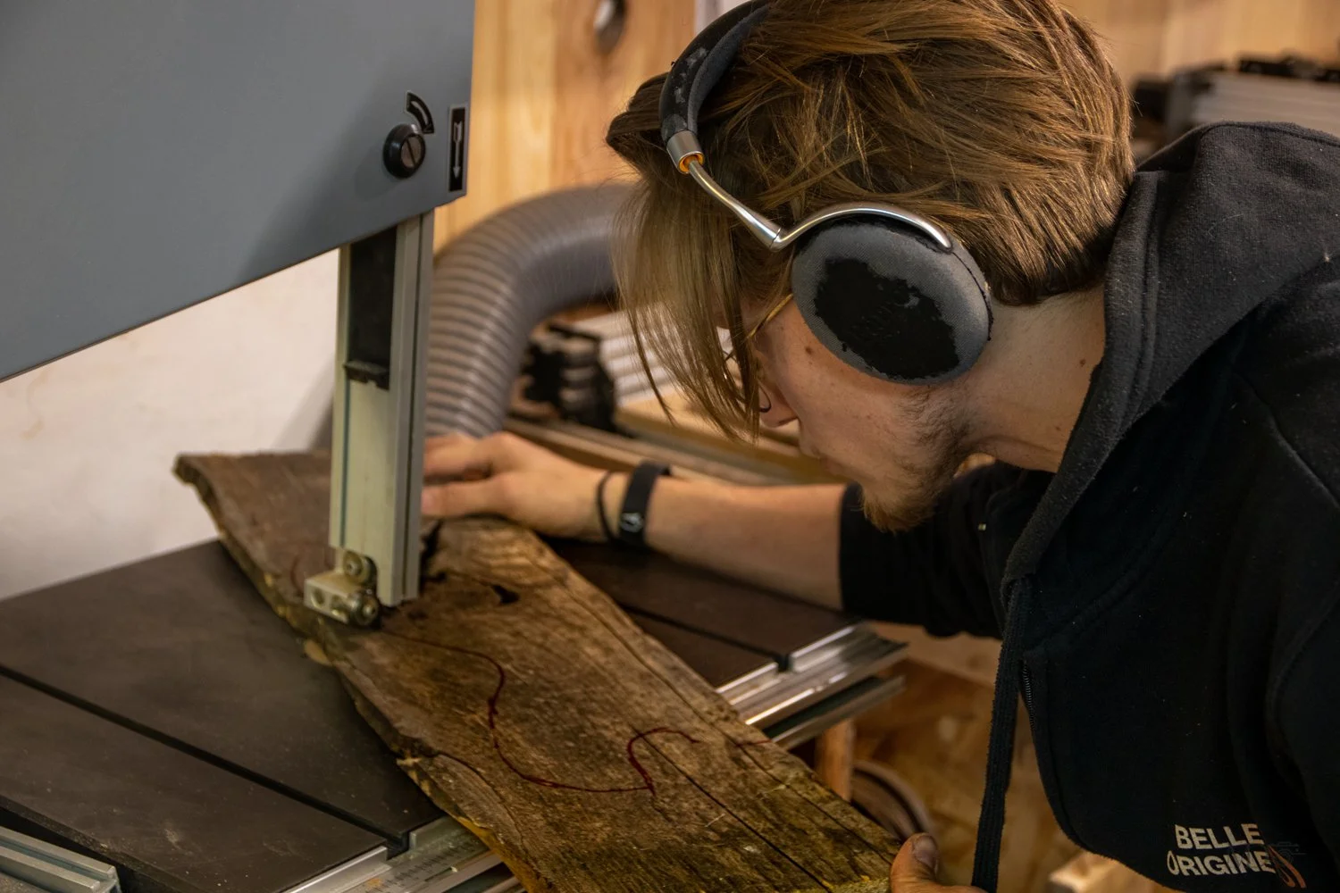 Un homme utilisant une machine à mesurer pour prendre des mesures sur une pièce de bois, dans un atelier.