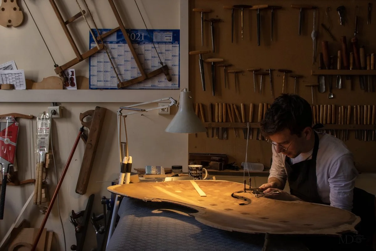 Un homme travaillant sur une guitare en bois dans un atelier.