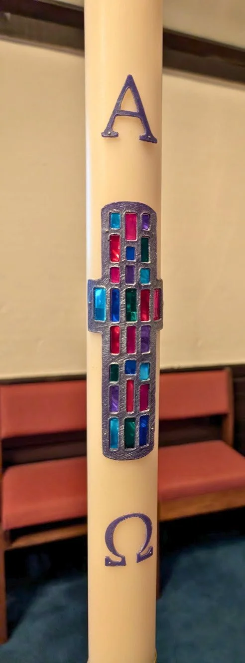 A candle with a purple letter A at the top, a colorful stained glass church in the middle, and a purple Omega symbol at the bottom.