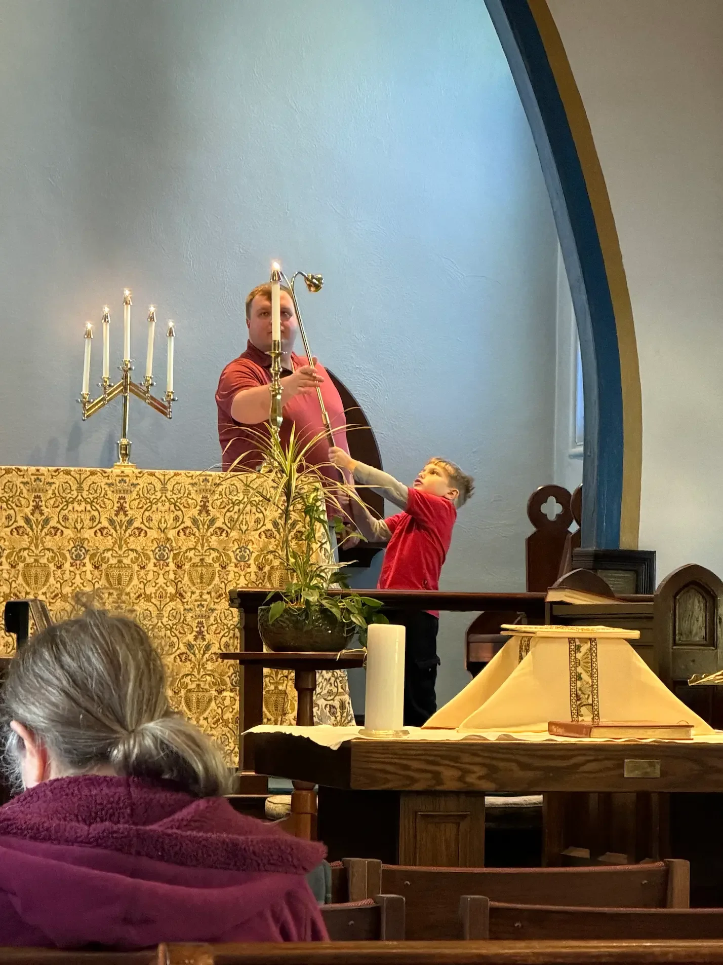 A child and an adult light candles for worship at an LGBTQ+ affirming Episcopal church in Newton Highlands