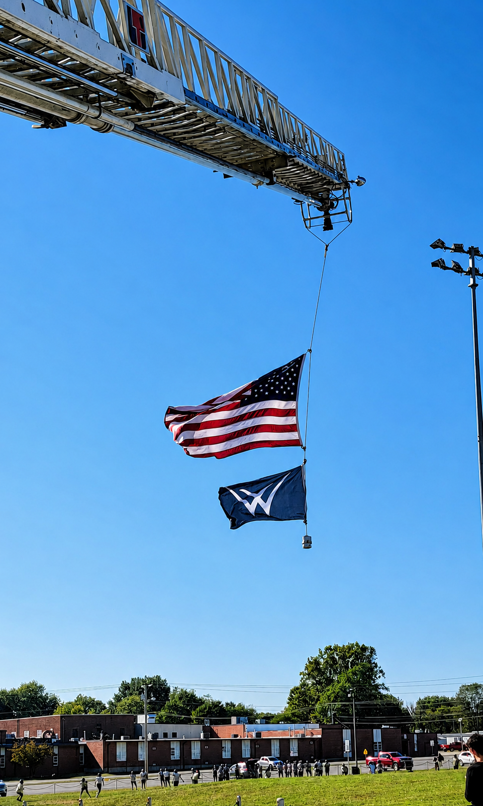 American and Willard Public Schools flags raised on fire truck ladders with Willard Middle School in the background