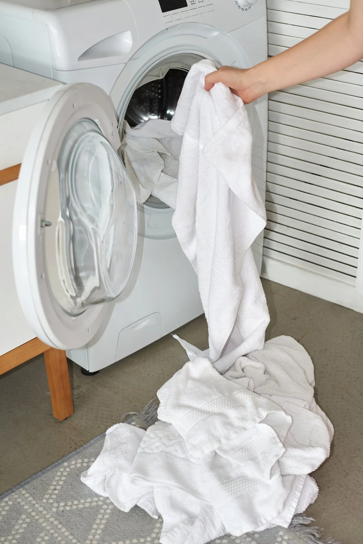 Ridge Haven - New Townhomes for Rent in Concord |  Clothes being taken out of a front-loading washing machine. Several white towels and cloths are on the floor and inside the open door of the washing machine.