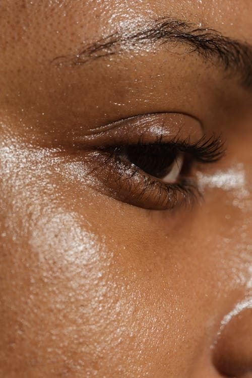 Primer plano del ojo de una persona con su piel aceitosa y húmeda.