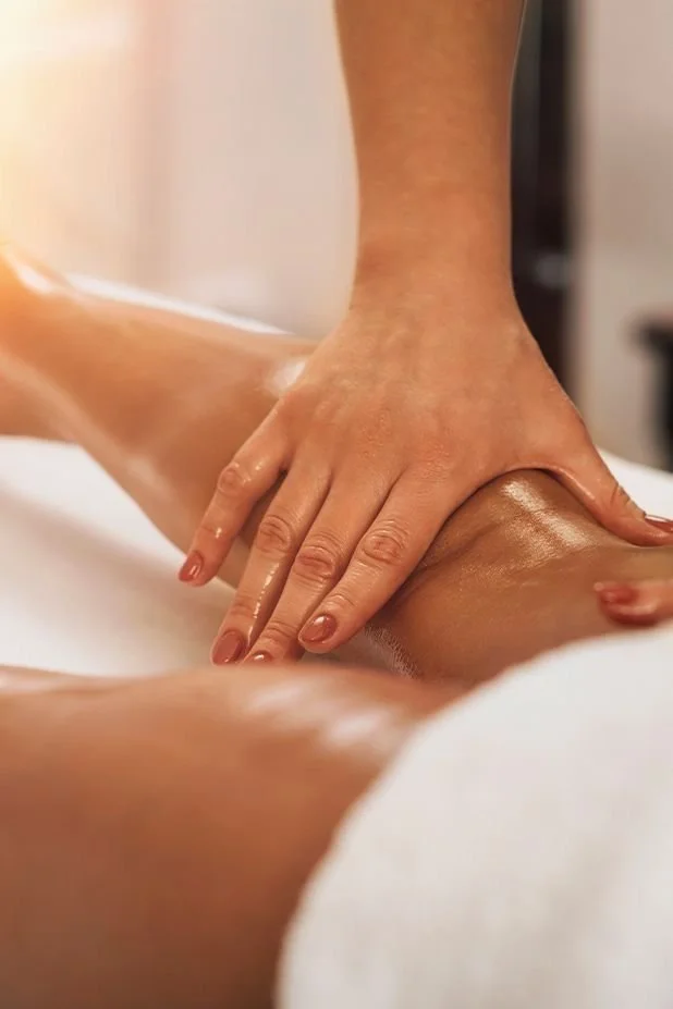 Una persona recibe un masaje en la pierna y muslo en un ambiente de spa o centro de masajes.