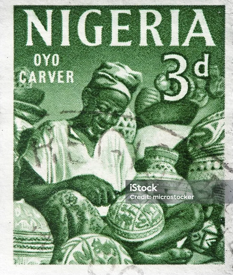 Green Nigeria postage stamp featuring a man in traditional attire, creating pottery with decorated clay vessels around him.