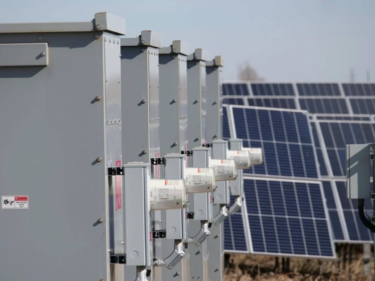 Multiple solar panels installed outdoors with electrical boxes in the foreground.