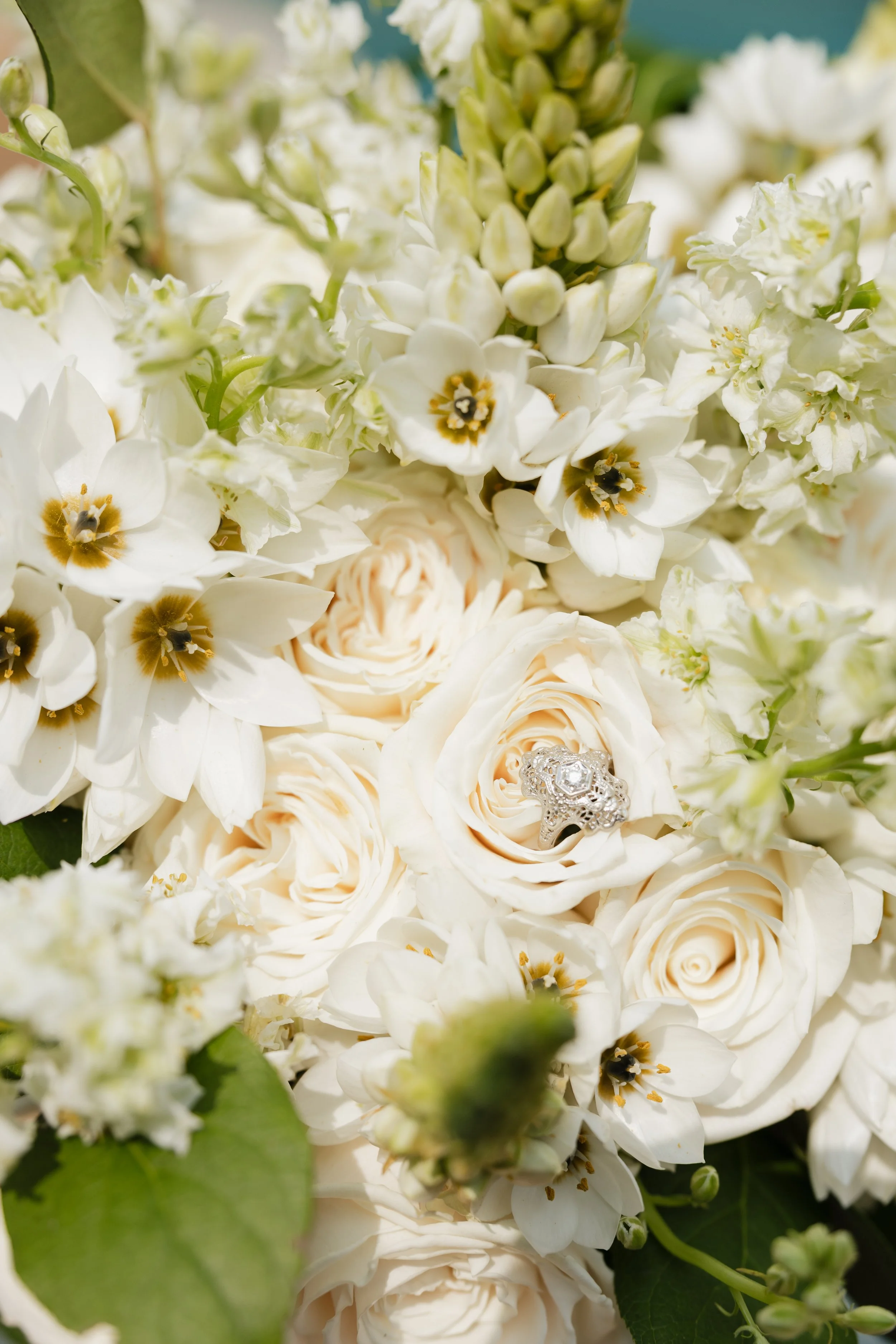 Close-up of a bouquet of white flowers with a diamond engagement ring placed among the blooms.