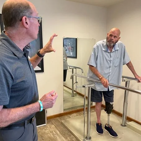 Jeff Coniway assists a patient after fitting them with a prosthetic leg.