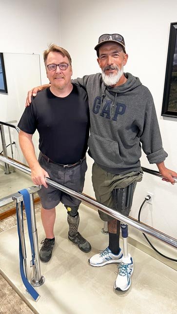 “Eddie, a One Leg At A Time recipient, standing beside a Quorum prosthetist while wearing his new lower limb prosthesis. Learn more about Eddie’s story and prosthetic care.
