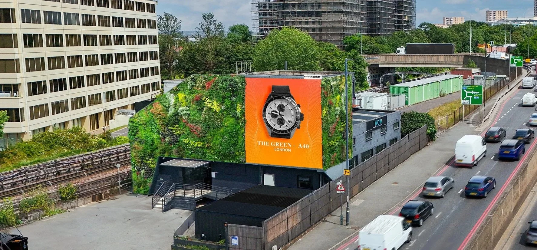 City street with cars, a billboard with a large watch ad, buildings, green trees, and highway signs in London.