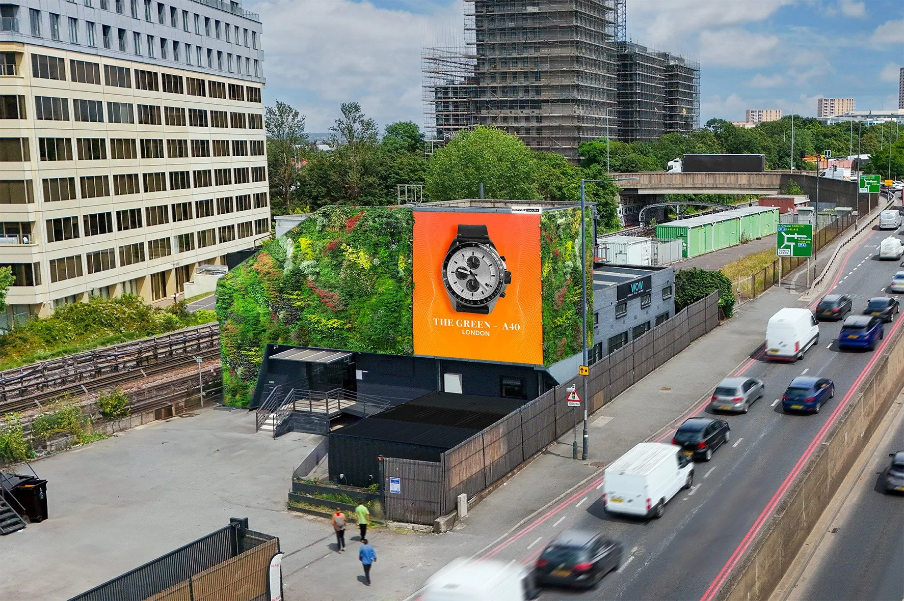 A city street with a large billboard advertising a wristwatch, flanked by a green wall and surrounded by buildings, with cars and pedestrians visible.