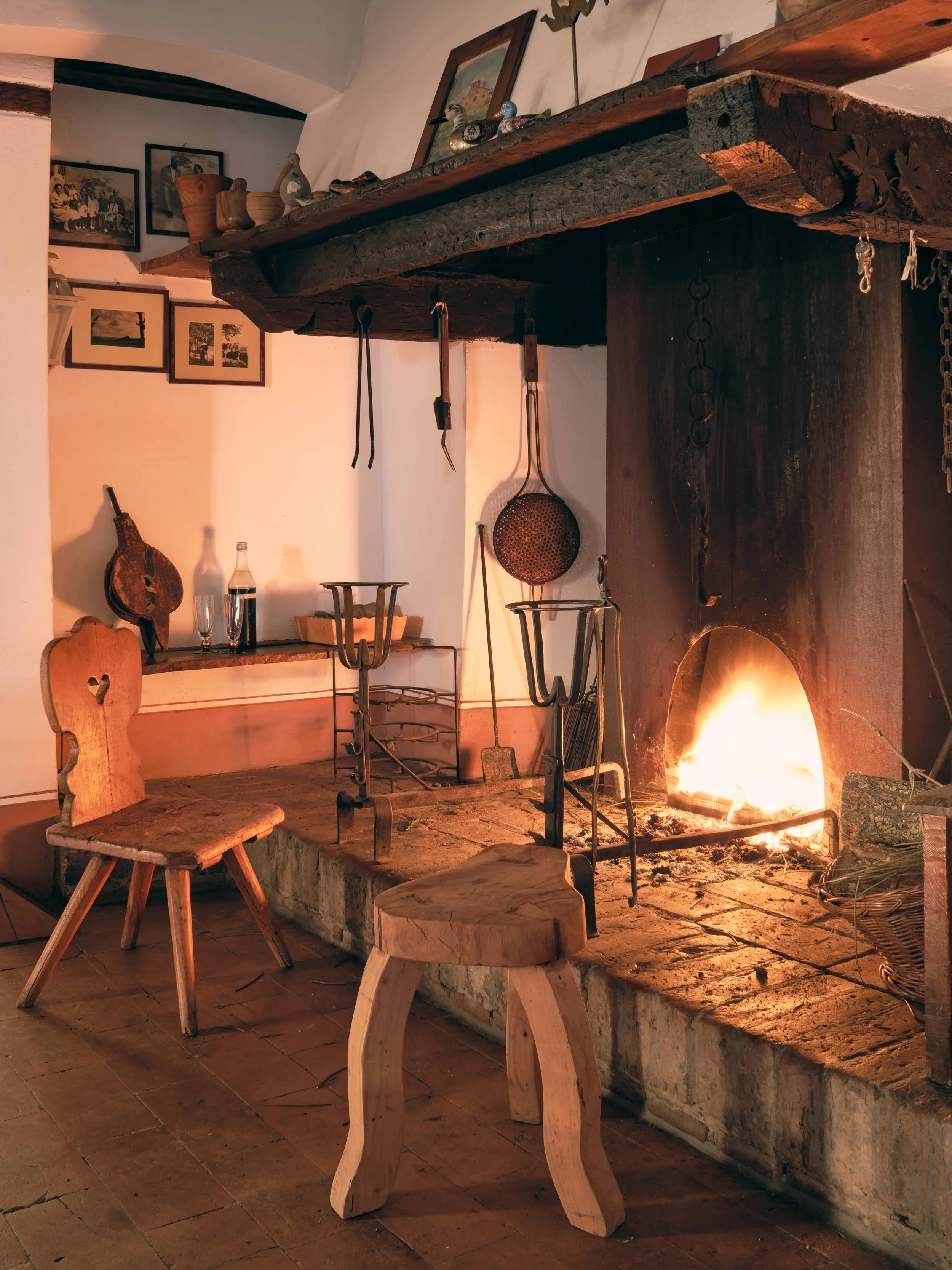Cozy room with wood furniture, a fireplace with a fire, and framed photos on the wall.