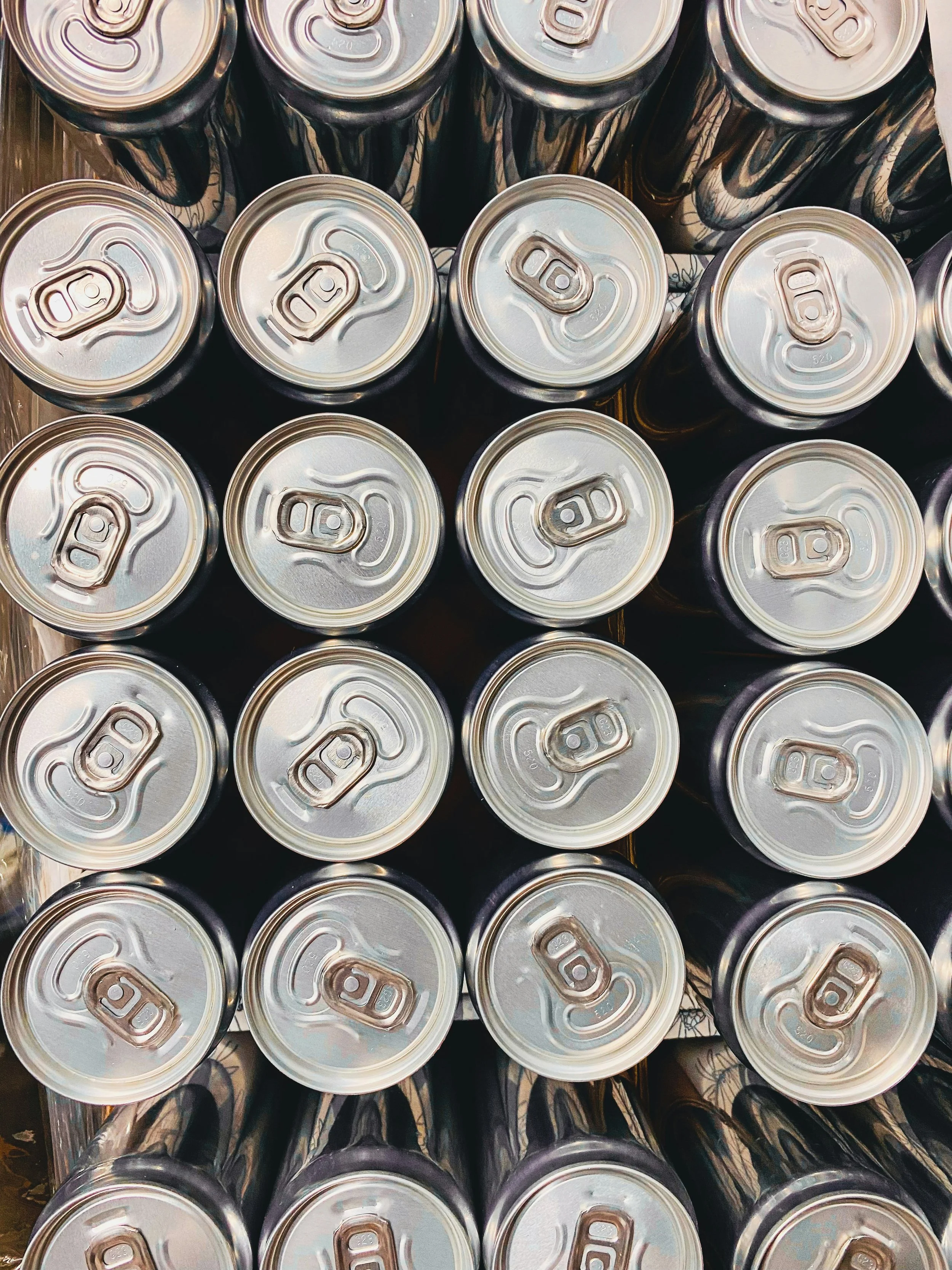 Top view of multiple aluminum soda cans arranged in a grid pattern.