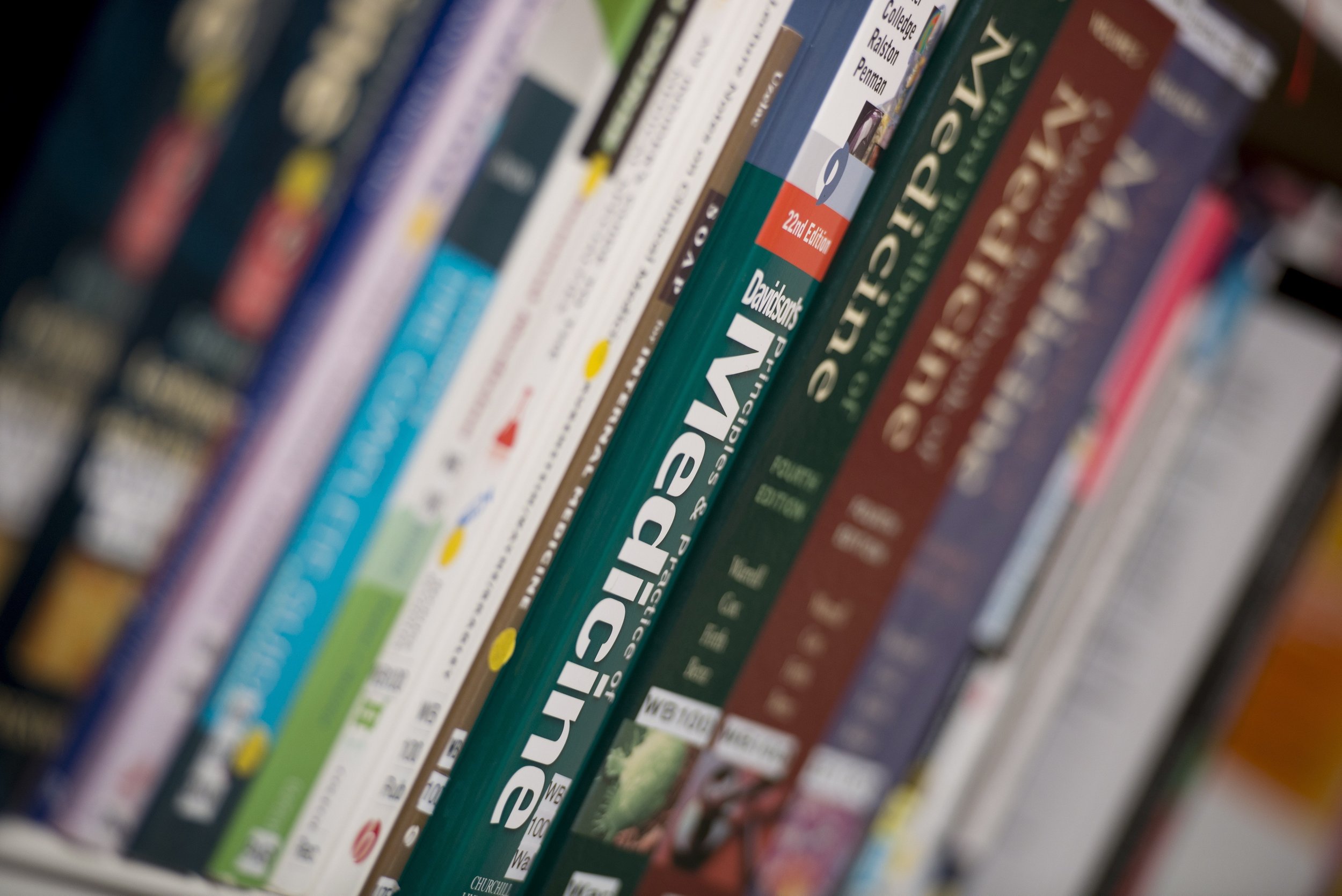 Close-up of a bookshelf with various colorful books arranged vertically, some titles partially readable including 'Psychology' and 'Davidson'.