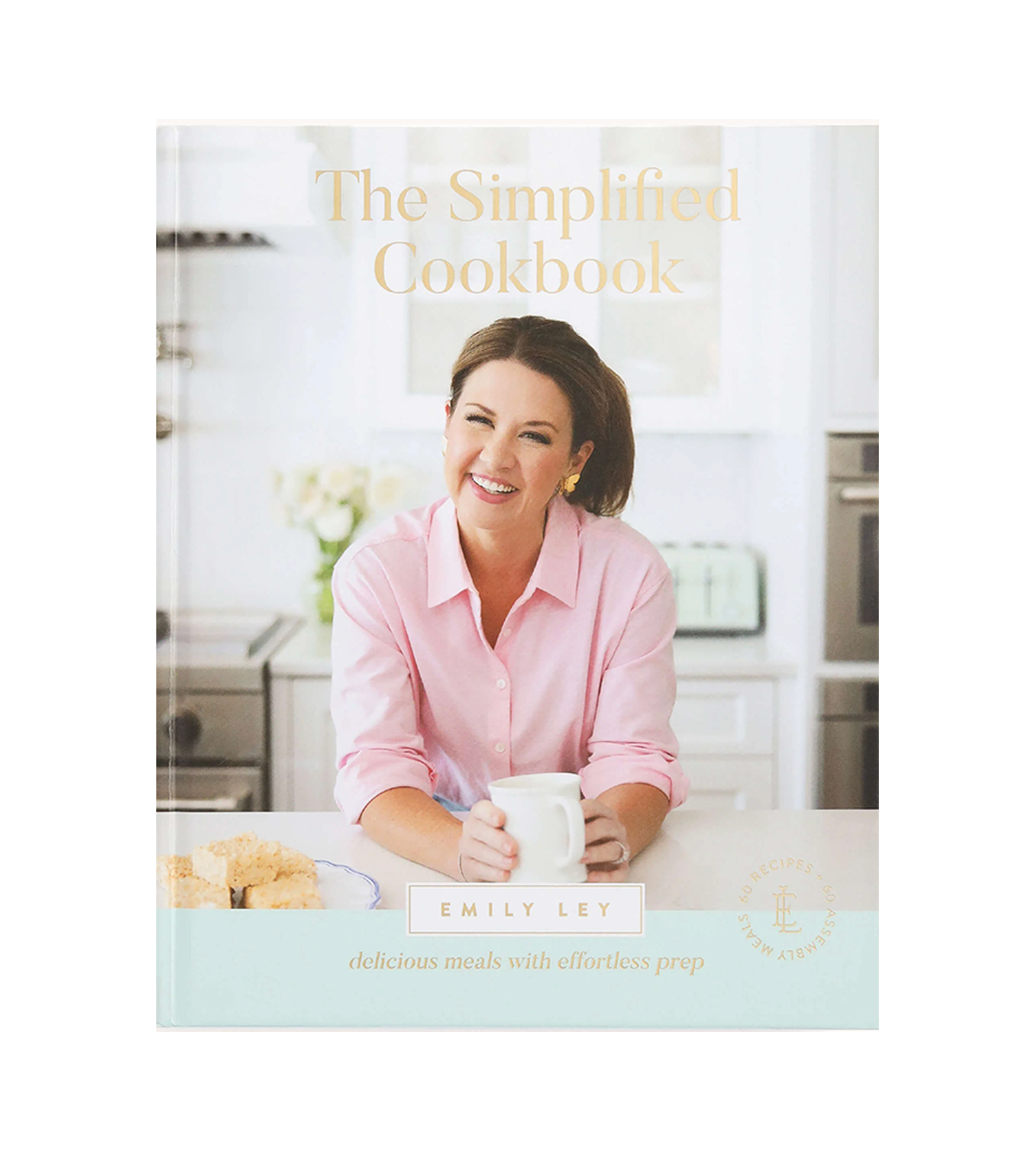 Book titled 'The Simplified Cookbook' by Emily Ley with a woman smiling, holding a white mug, in a bright kitchen setting.