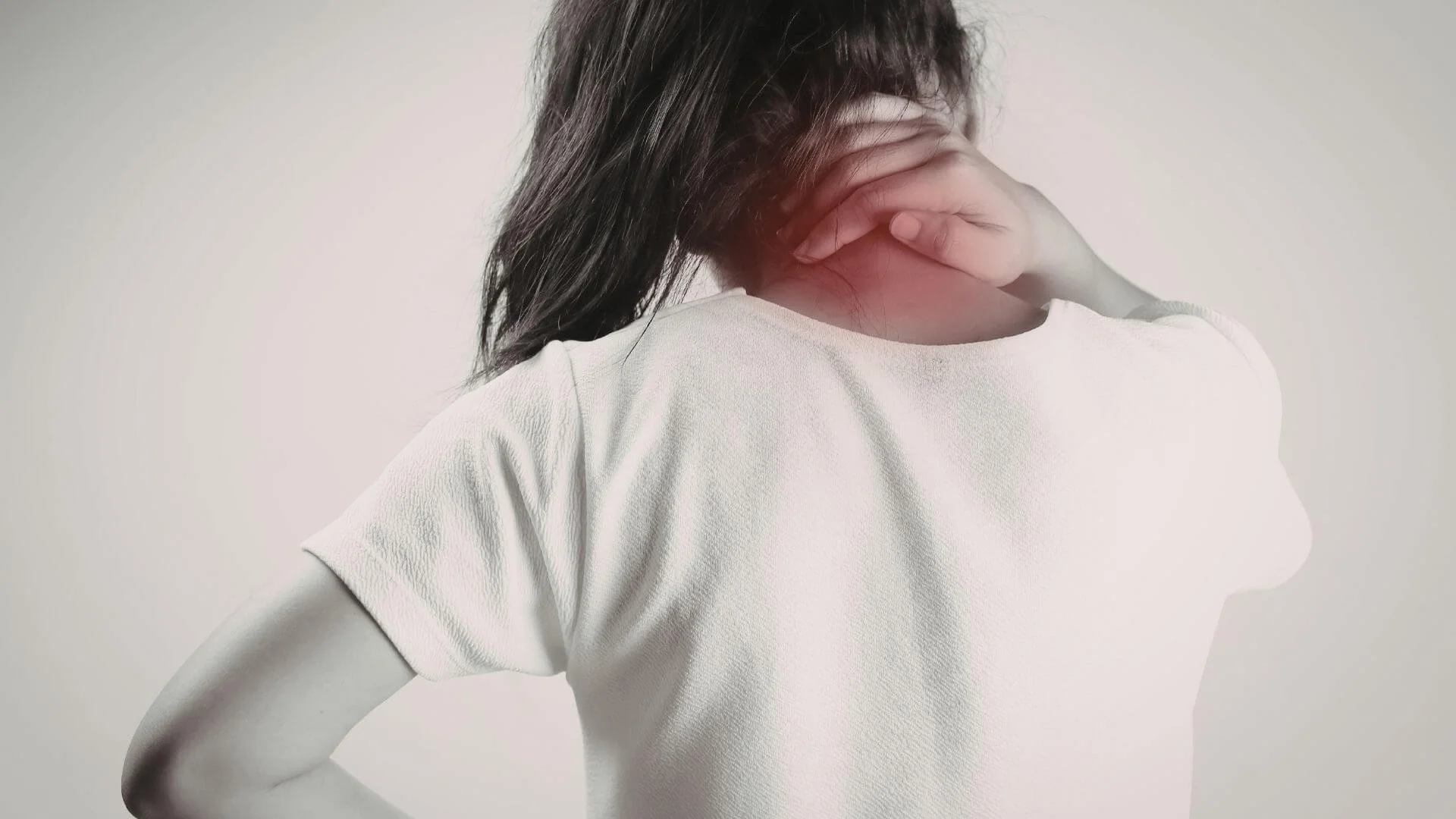 woman holding the back of her neck in pain