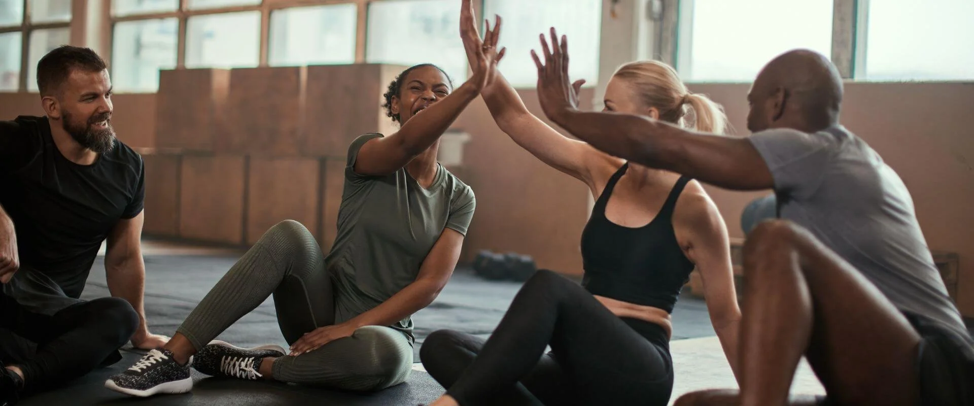 Group of people doing a high-five while sitting on the gym floor