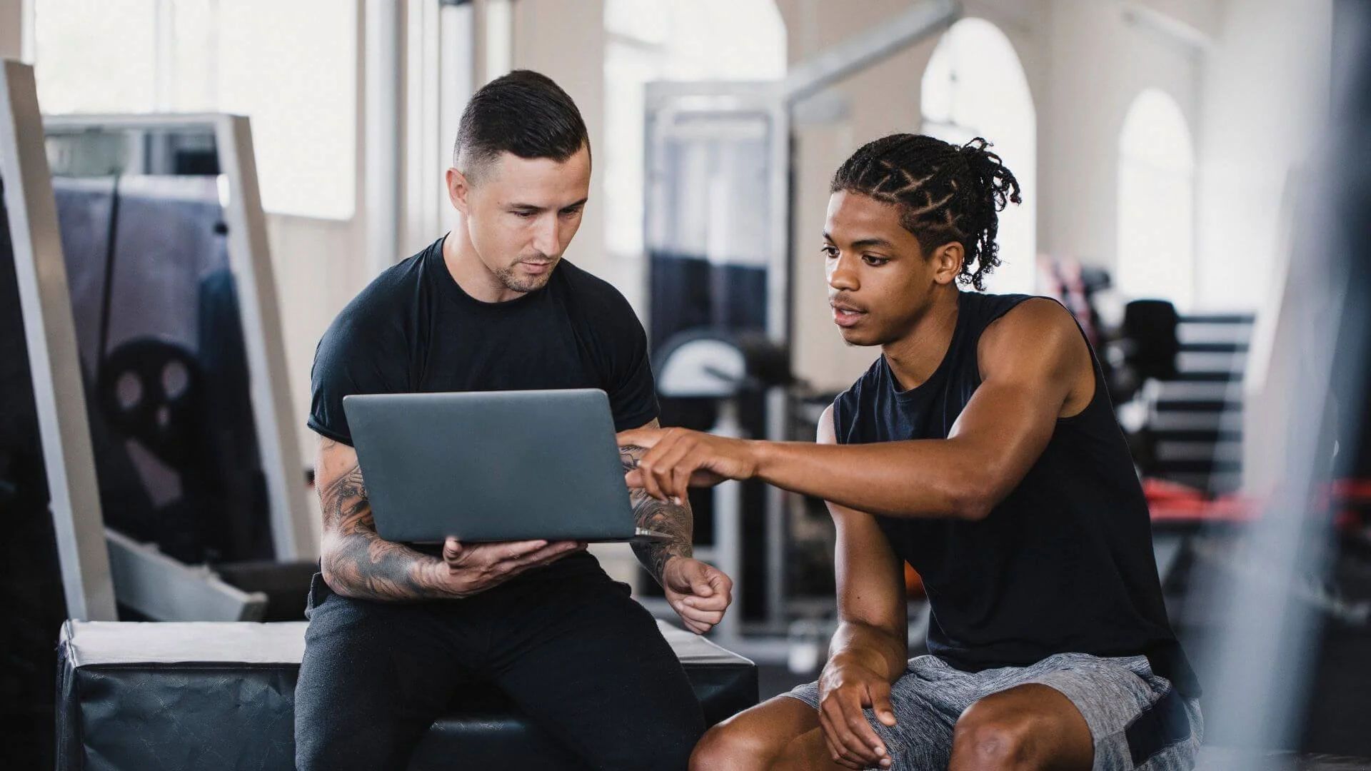 man talking with his personal trainer to understand how to reach his goals
