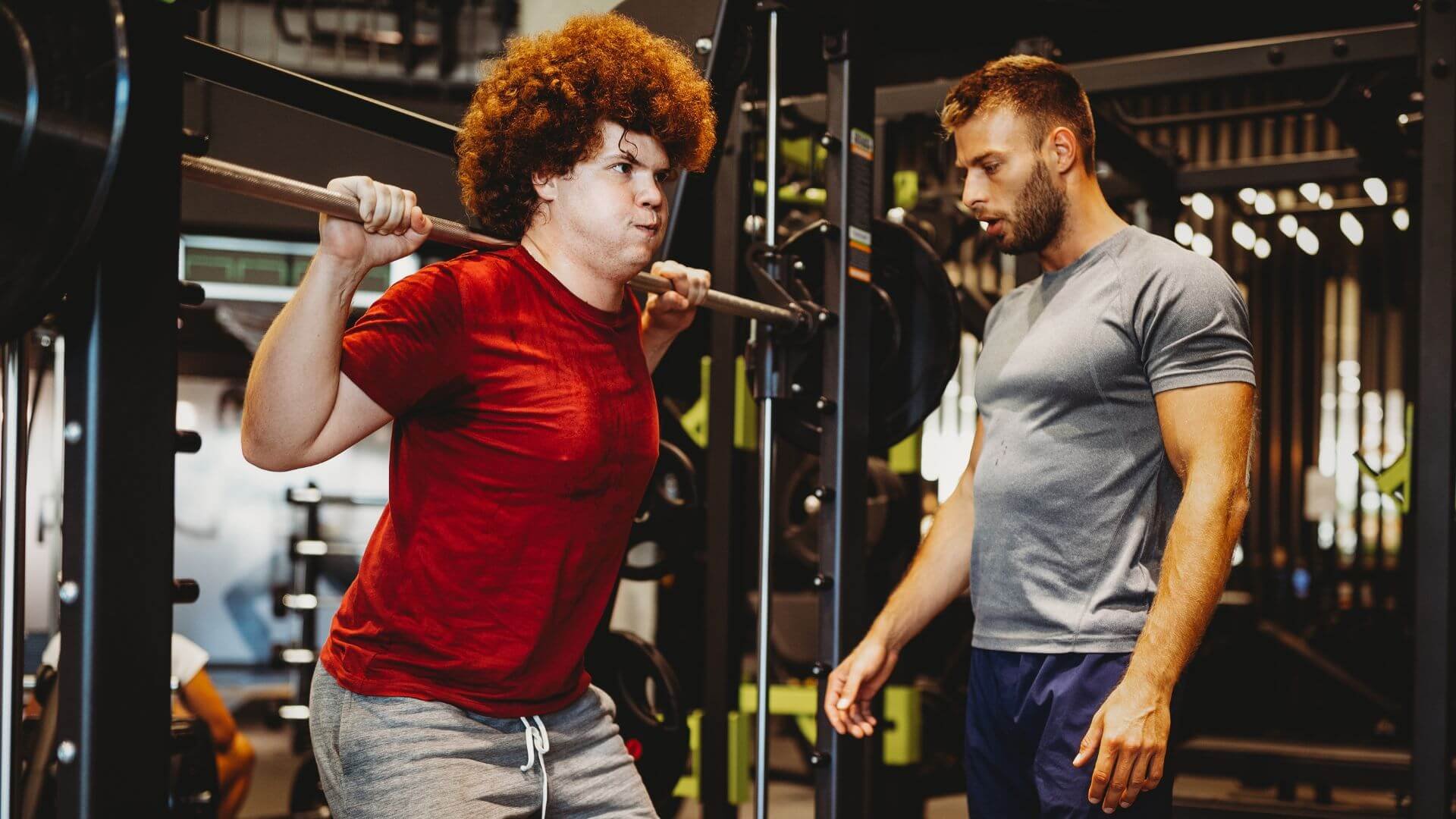 man exercising while being watched by a personal trainer to help him lose weight