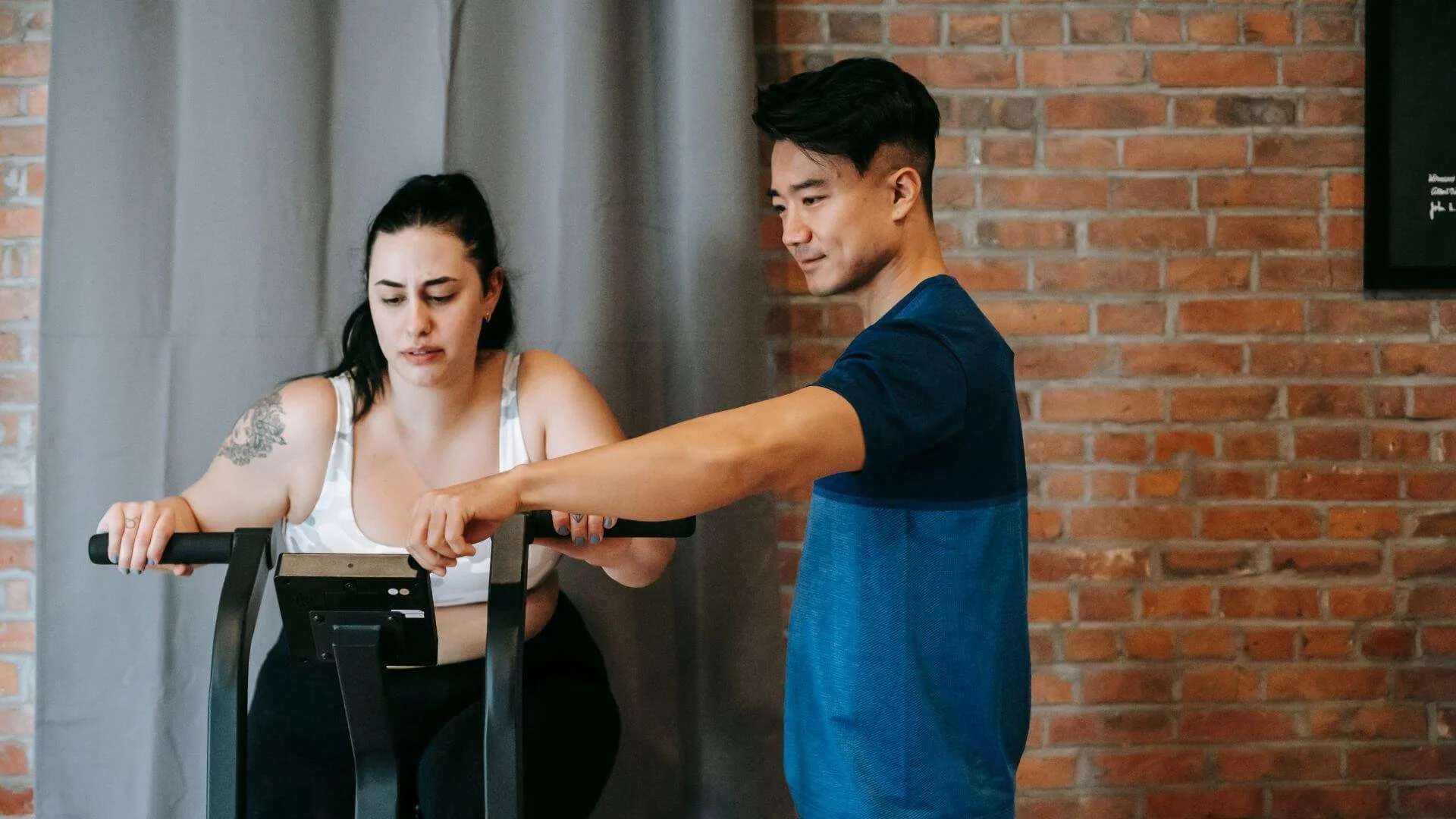 personal trainer helping a client on an exercise machine