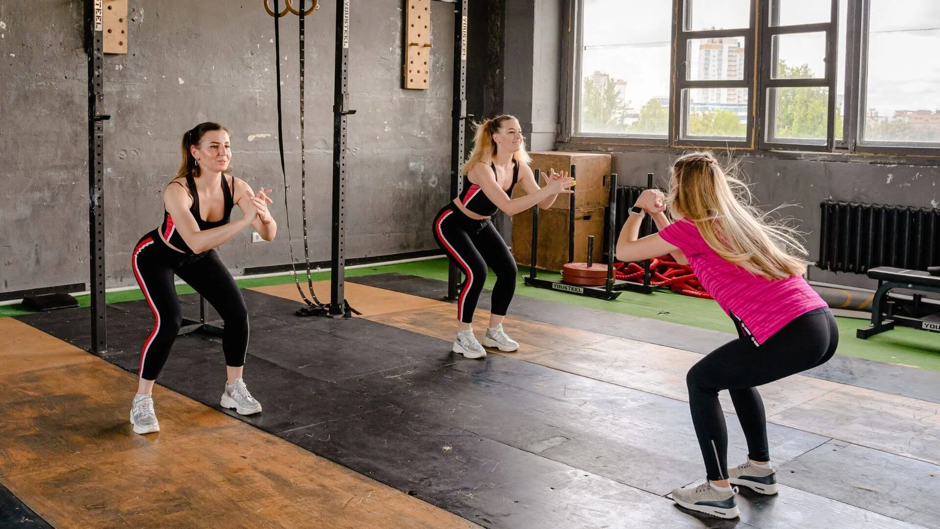 a personal trainer leading two clients in hard leg exercises