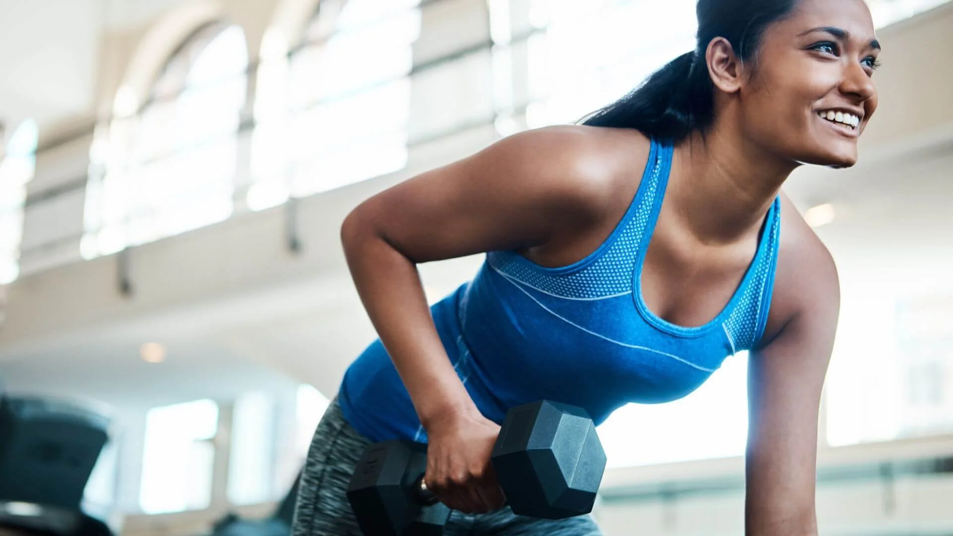 woman smiling with lifting a weight and exercising every day