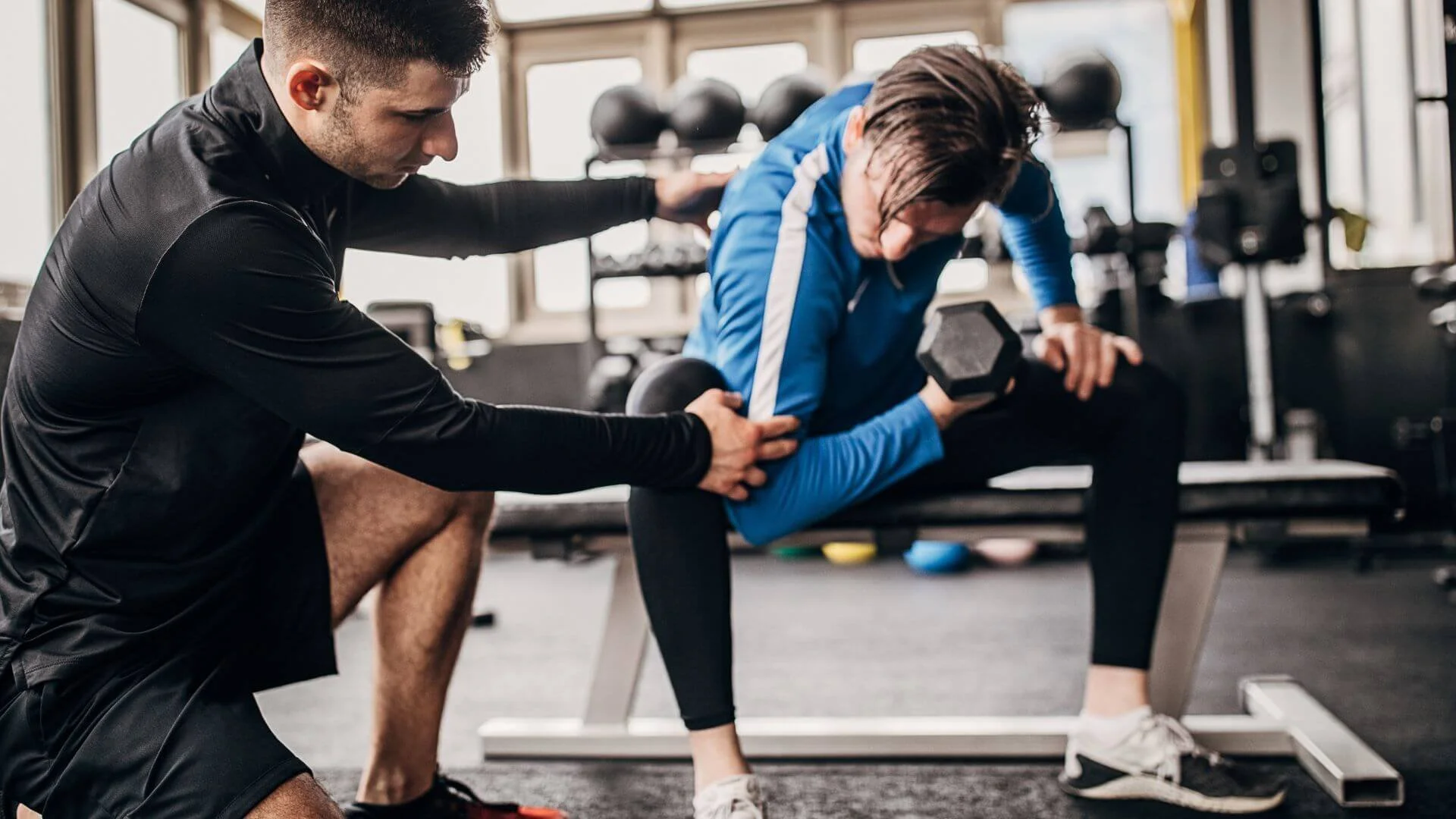 male personal trainer helping a male client train