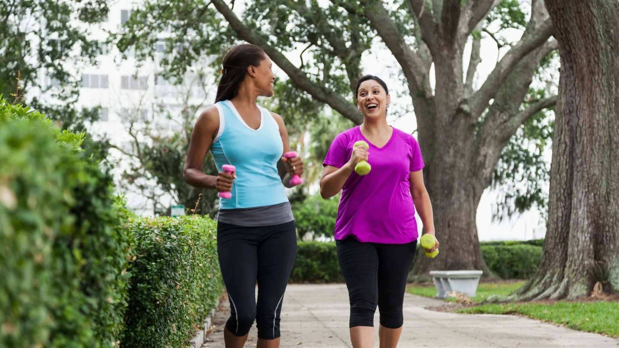 two women smiling while walking with weights